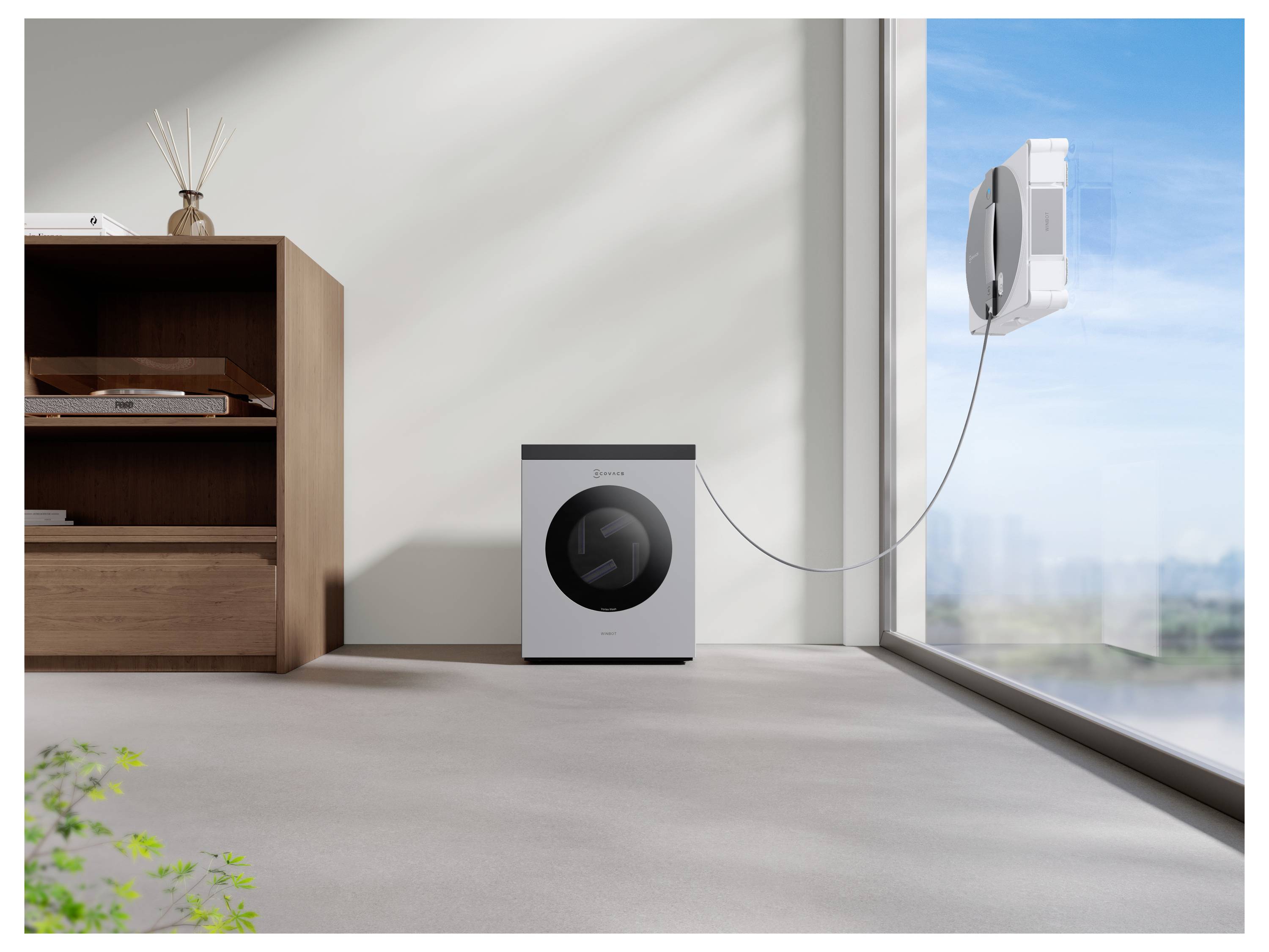 Ein Fensterputzroboter ist an einem großen Fenster befestigt. Eine Waschmaschine mit Trockner steht in der Nähe in einem minimalistischen, sonnendurchfluteten Raum.