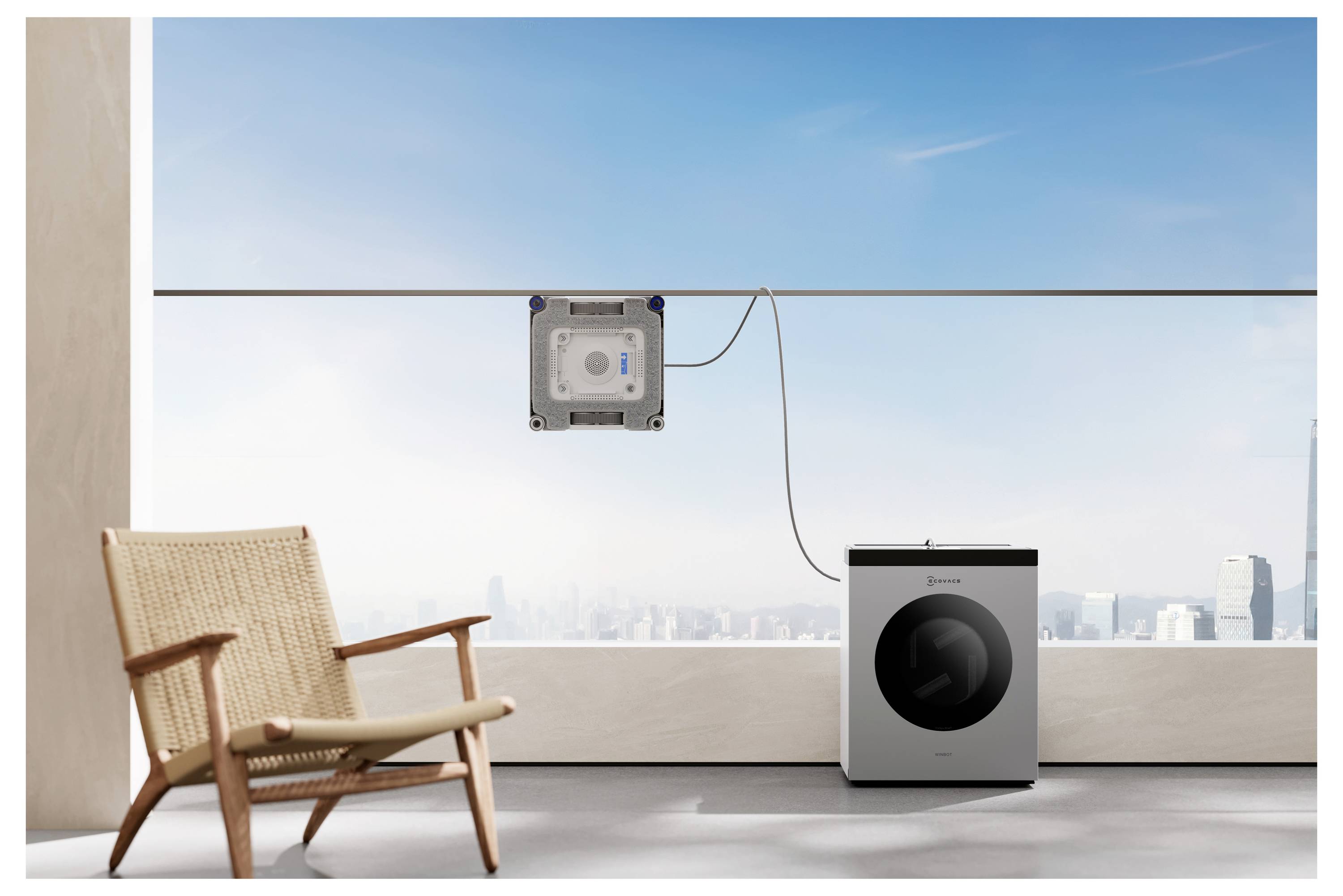 Ein robotischer Fensterreiniger ist an einem großen Fenster mit freier Himmelssicht befestigt, neben einer modernen Waschmaschine und einem Korbstuhl.