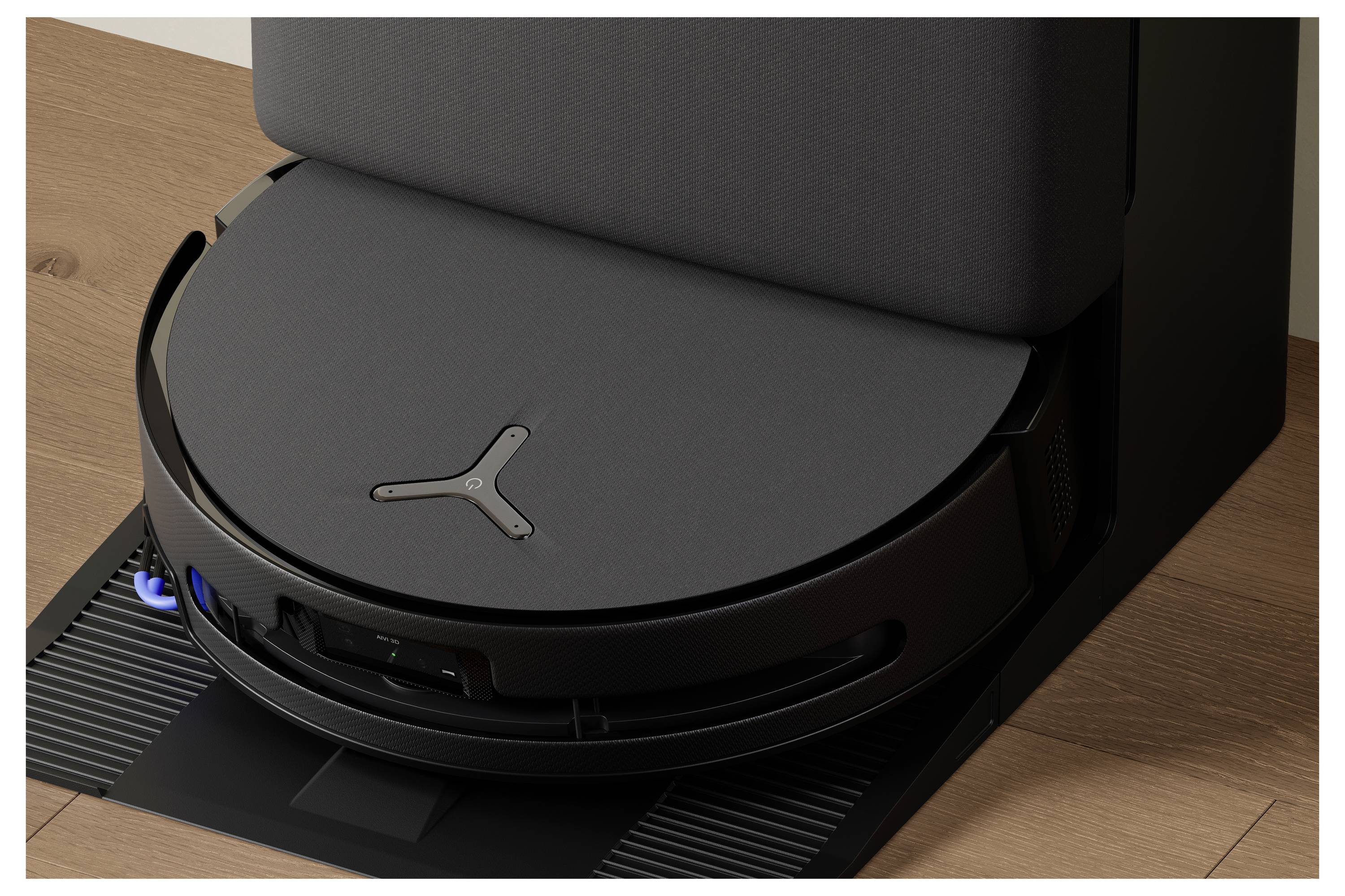 Ein Staubsauger-Roboter, der an seiner Ladestation auf einem Holzboden andockt.