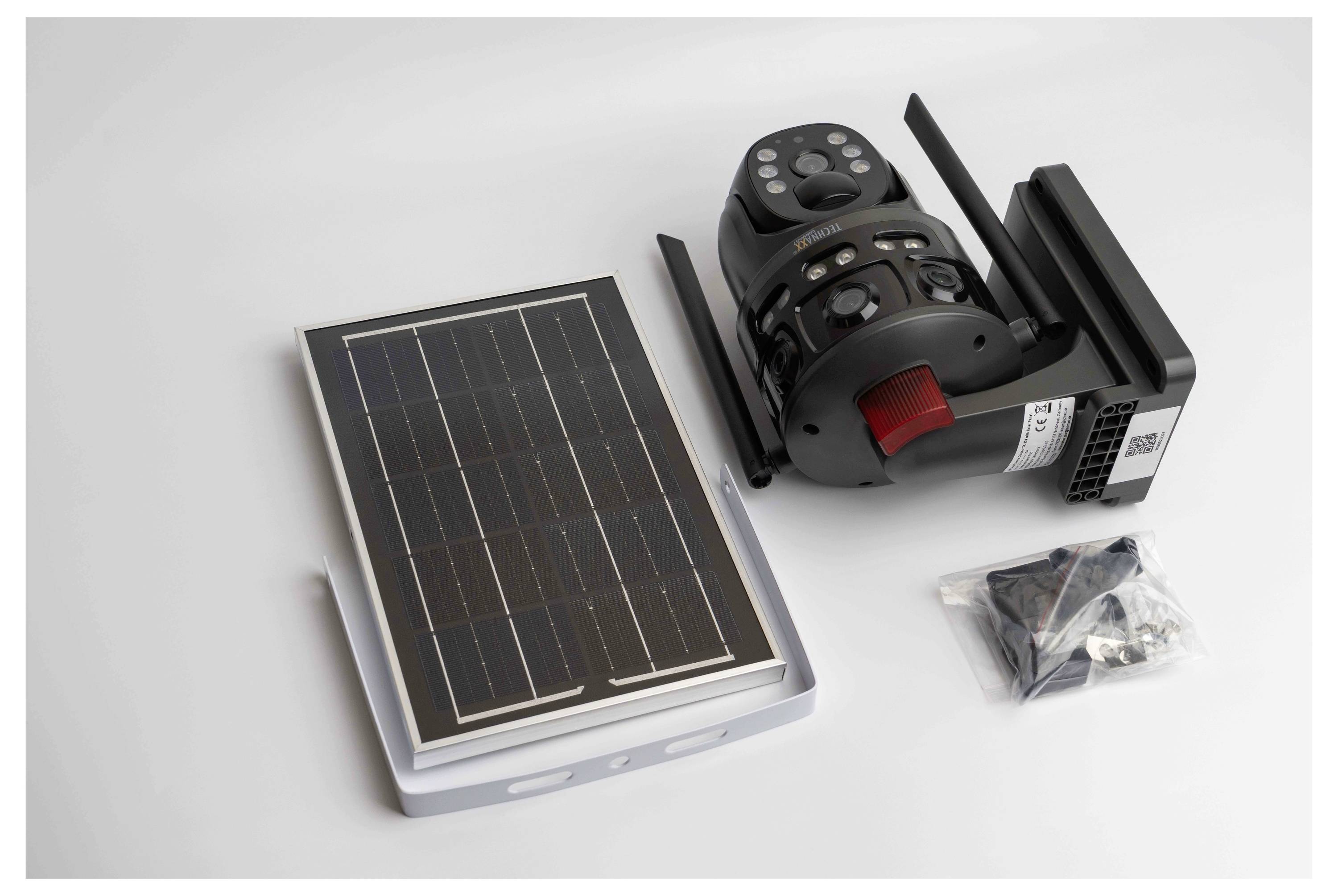 Solarmodul, Kameraausrüstung mit rotem Akzent und kleine Tasche mit Zubehör auf weißem Hintergrund.