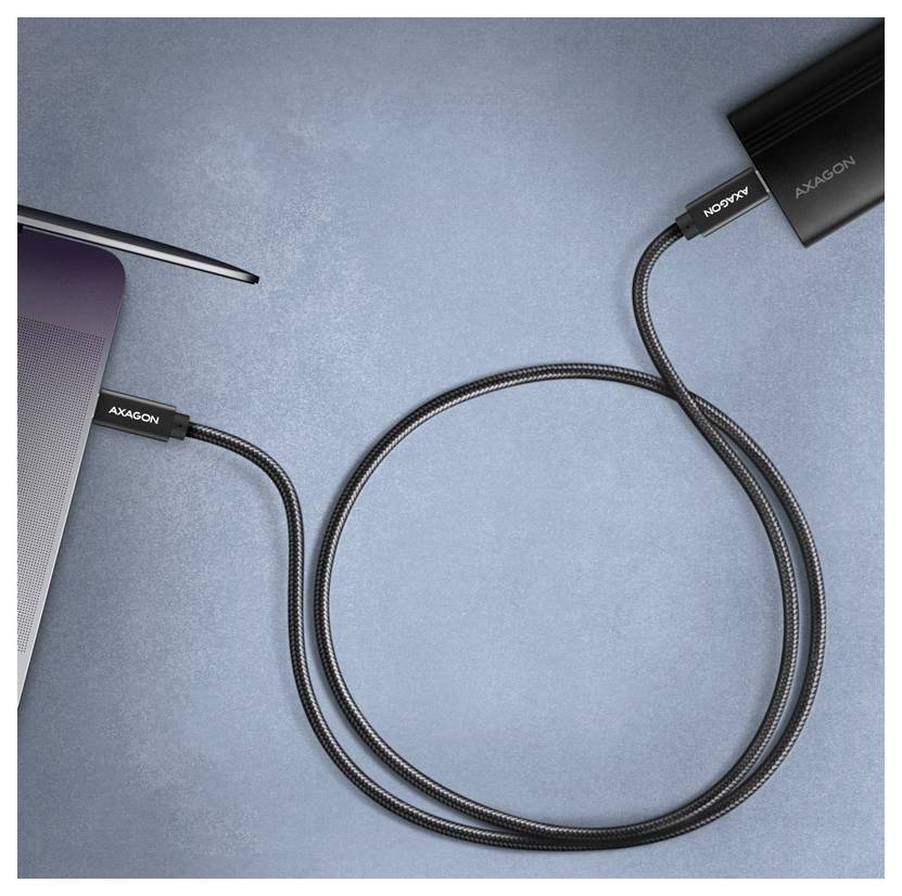 Nahaufnahme eines Laptops, der mit einem schwarzen AXAGON-Kabel und einem Adapter auf einer blauen Oberfläche verbunden ist.