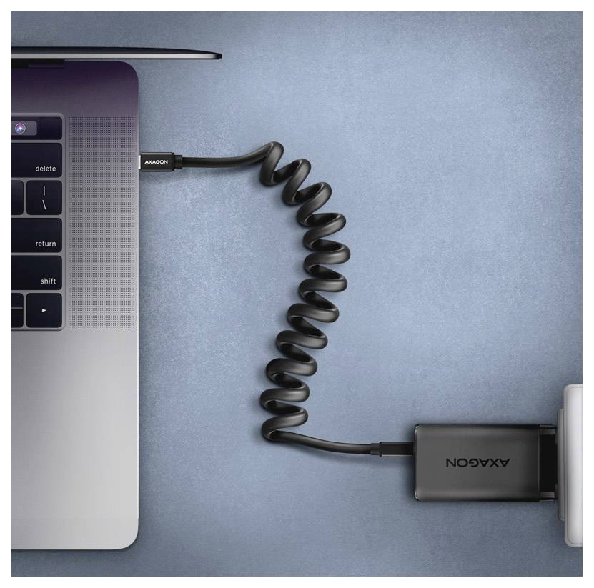 Obere linke Ecke eines Laptops, der mit einem aufgerollten schwarzen Kabel und Adapter auf blauem Hintergrund verbunden ist.