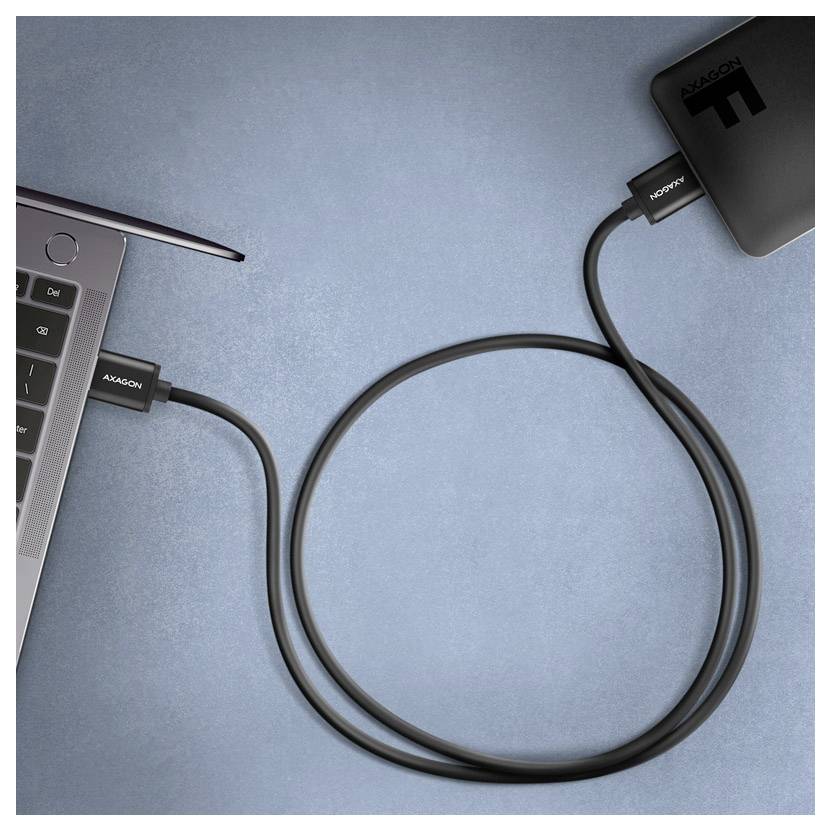 Laptop, der über ein USB-C-Kabel mit einer externen Powerbank auf einer blauen Oberfläche verbunden ist.