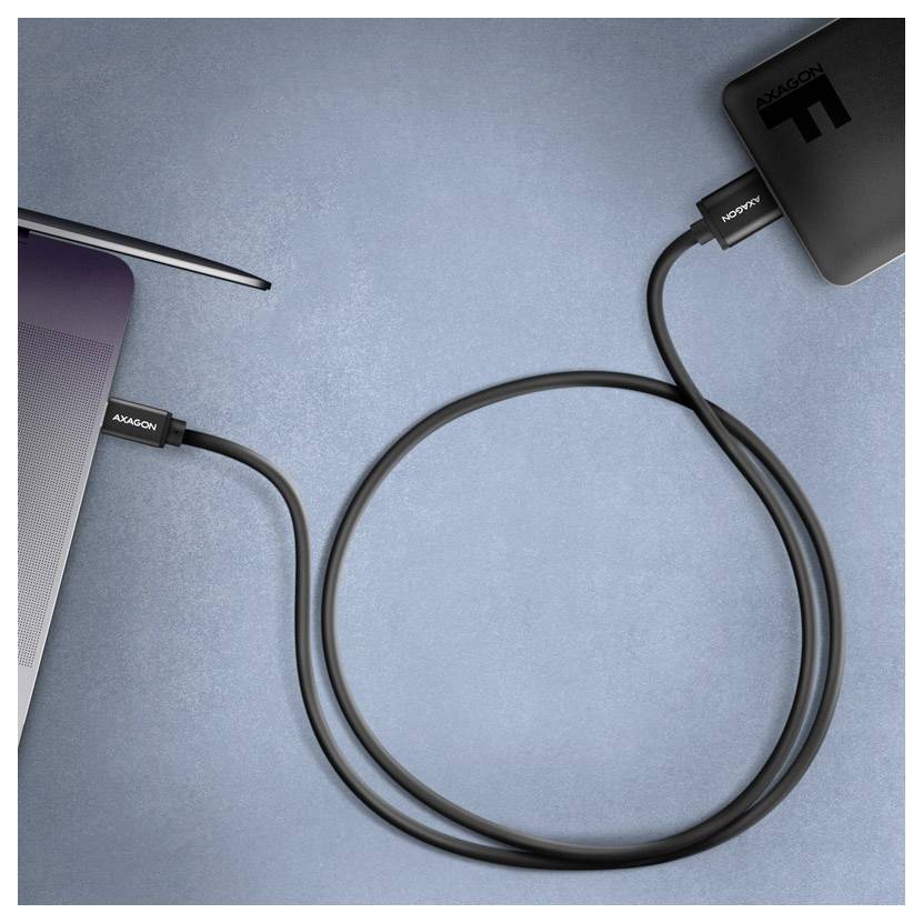 Laptop, der über ein USB-C-Kabel mit einem Smartphone auf einer blauen Oberfläche verbunden ist und eine Daten- oder Ladeverbindung anzeigt.