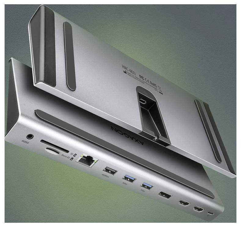 Silberne Laptop-Dockingstation in Perspektive dargestellt, mit mehreren vorderen Anschlüssen einschließlich Audio, USB, Ethernet und HDMI, sowie einem aufrechten Ständerabschnitt.