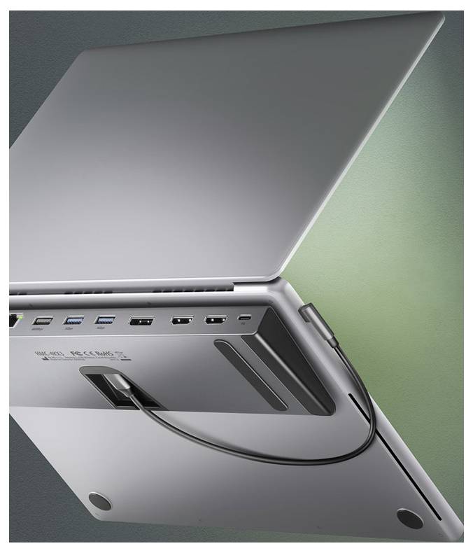 Nahaufnahme der Unterseite eines silbernen Laptops mit einem angesteckten Verbindungskabel in einem Anschluss, die Seitenports und Belüftungsöffnungen vor grünem Hintergrund zeigt.