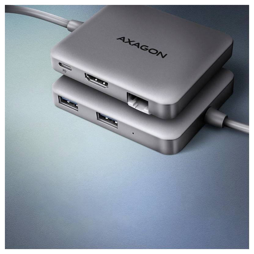 Zwei übereinander gestapelte AXAGON USB-Hubs auf einer blauen Oberfläche, die mehrere USB-Anschlüsse und angeschlossene Kabel zeigen.