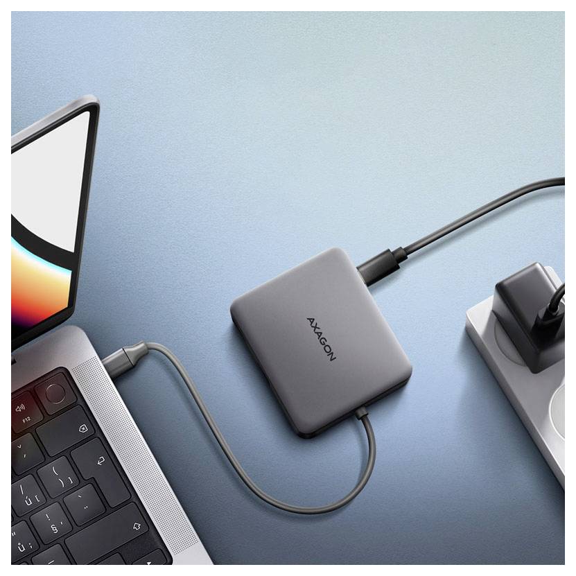 USB-C-Hub verbunden mit einem Laptop, Monitor und Netzteil auf einem blauen Schreibtisch.