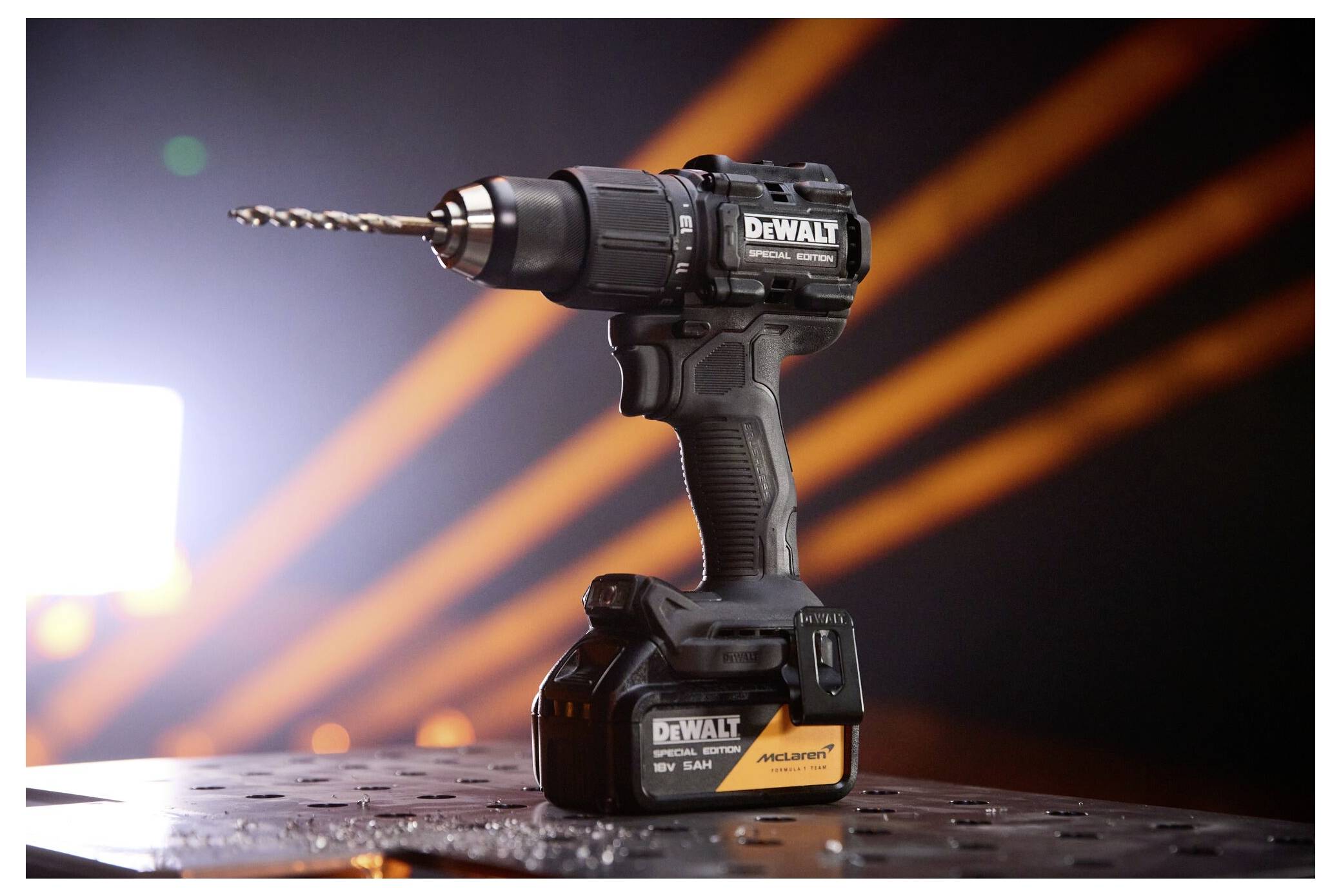 Ein kabelloses DeWalt-Bohrgerät/Schraubendreher mit angebrachtem Aufsatz sitzt auf einer Werkbank, beleuchtet vor einem dunklen Hintergrund mit orangefarbenen Lichtstreifen.