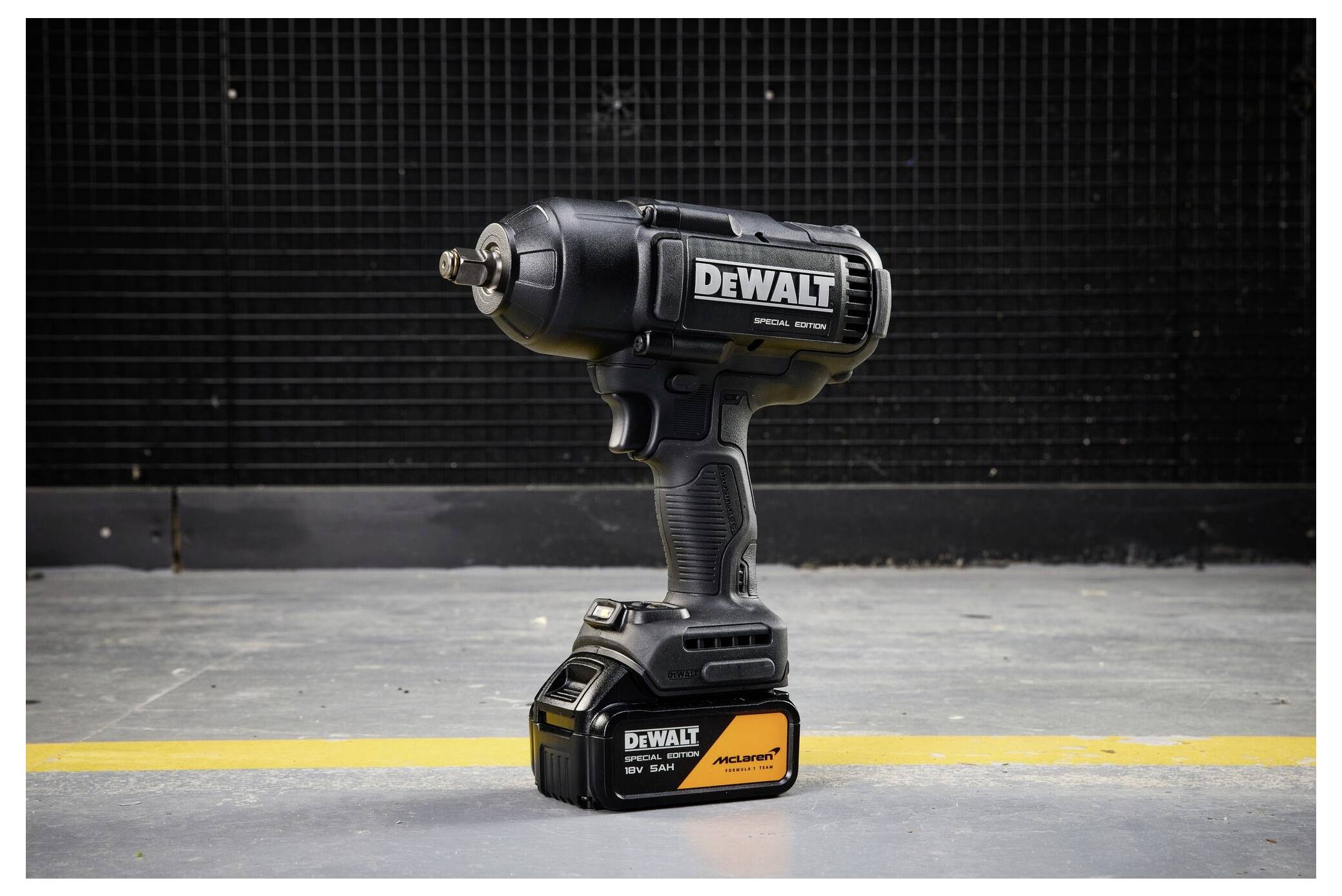 DeWalt Schlagschrauber ohne Kabel aufrecht auf einem Betonboden gegen eine dunkle Wand stehend, mit einer gelben Sicherheitslinie dahinter.