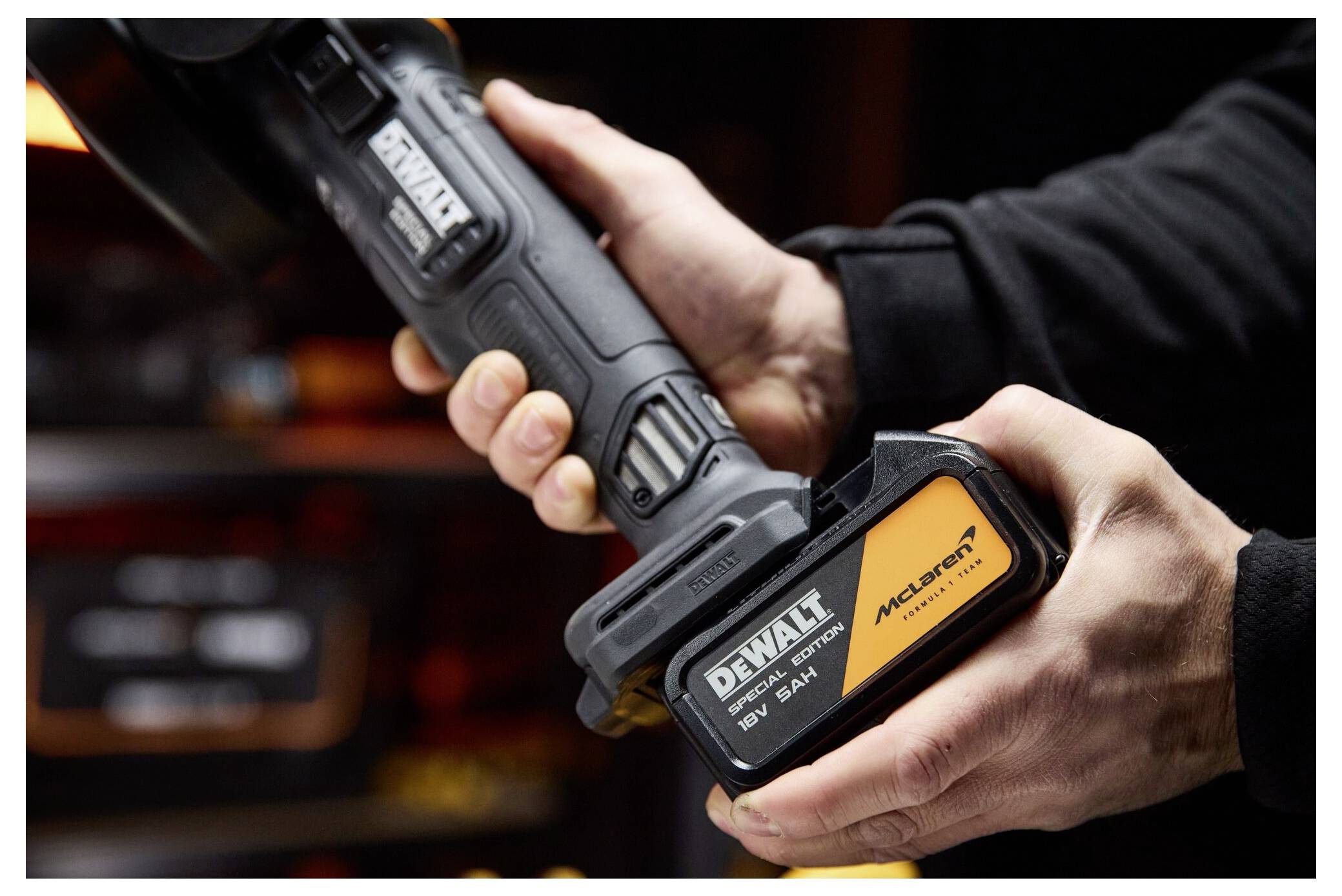 Hände halten ein DeWalt-Akku-Werkzeugpaket mit der Aufschrift „McLaren