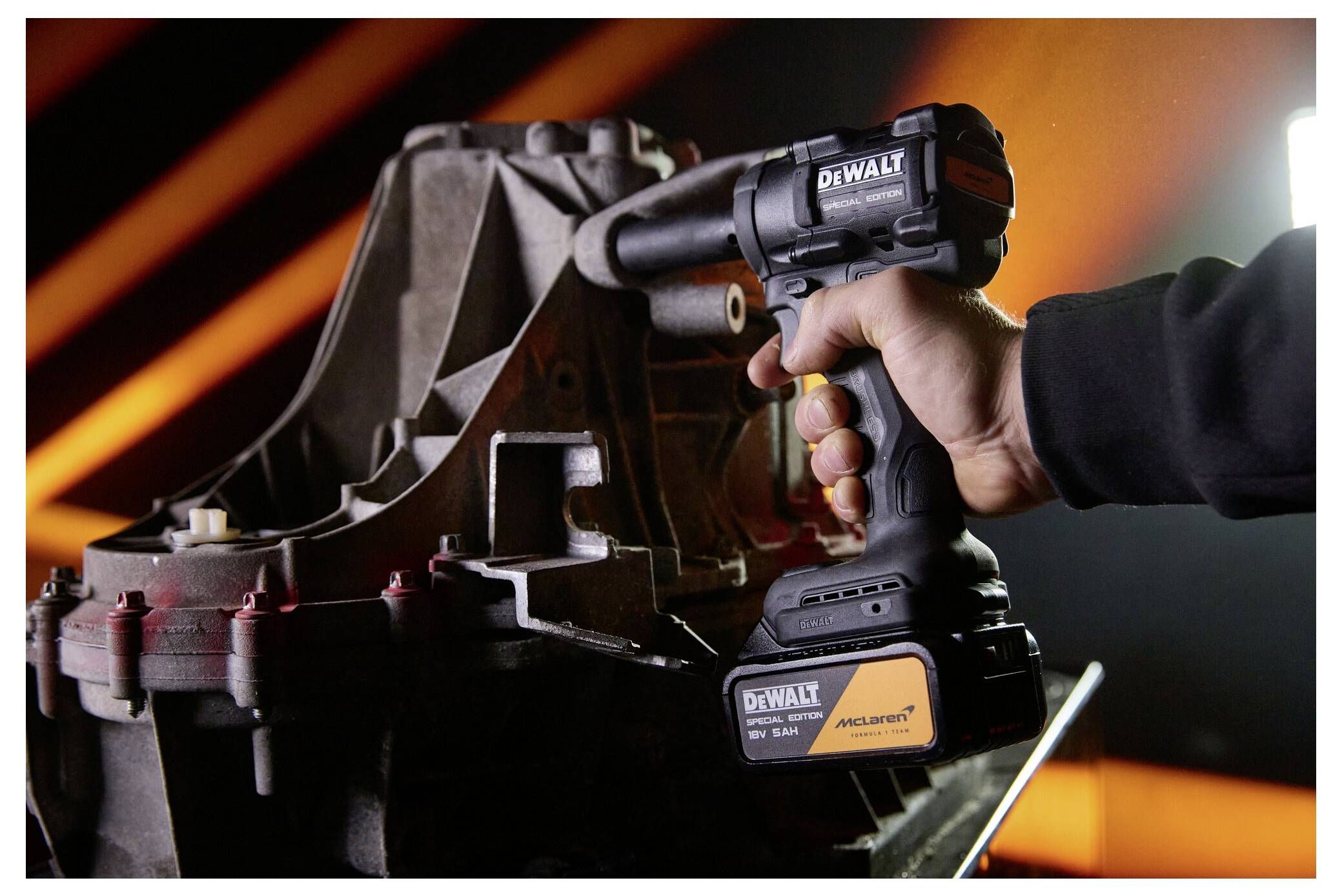 Hand, die eine DeWalt Akku-Schlagbohrmaschine in der Nähe eines Metallmaschinenteils in einer industriellen Werkstatt hält.