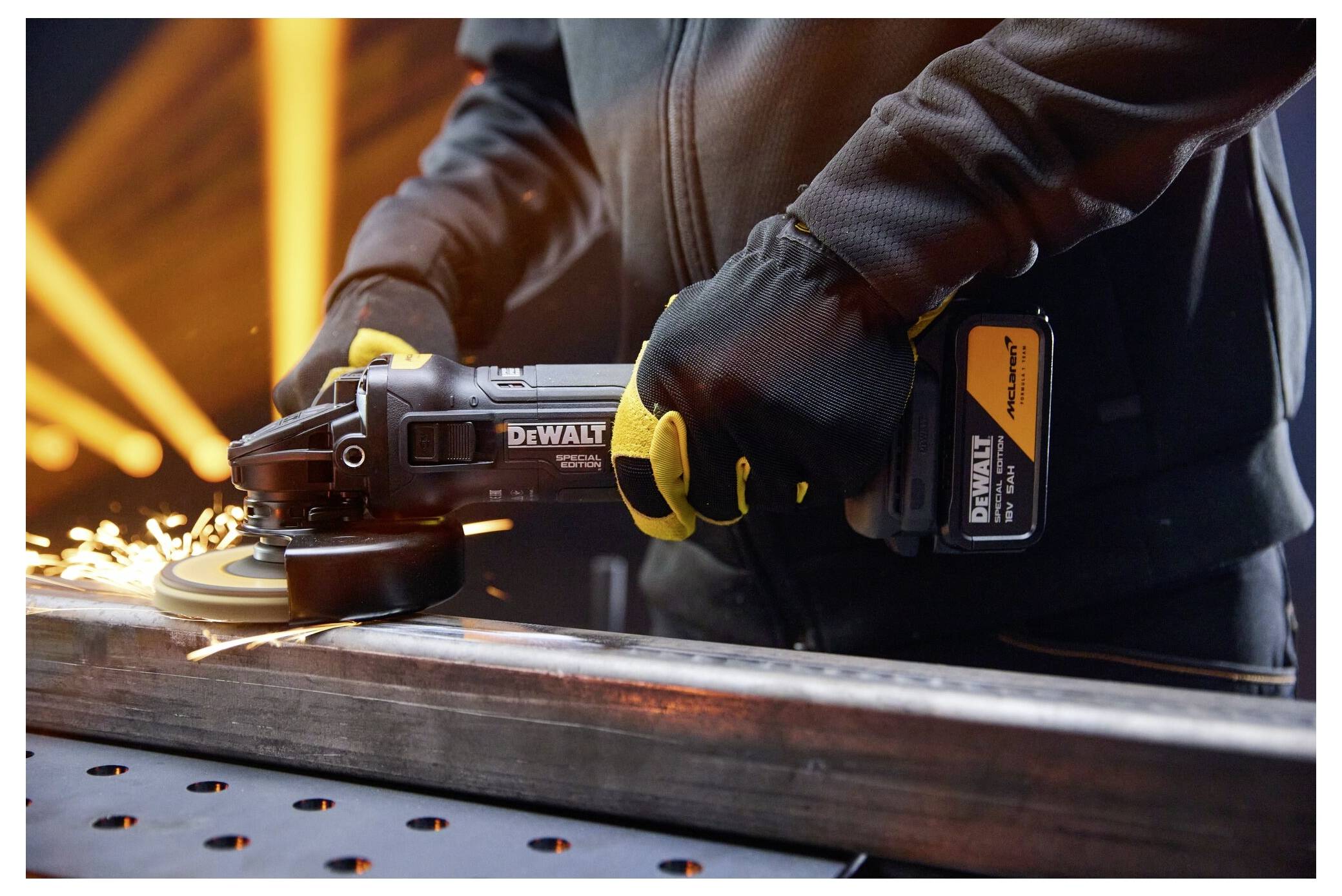 Arbeiter, der einen DeWalt-Winkelschleiffer verwendet, um einen Metallträger in einer Werkstatt zu schneiden, wobei Funken fliegen.