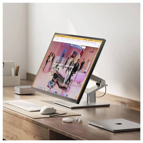 Ein Desktop-Monitor auf einem Ständer zeigt eine farbenfrohe Website oder ein Video an, aufgestellt auf einem Holzschreibtisch mit Tastatur, Maus, Kopfhörern und einem geschlossenen Laptop.