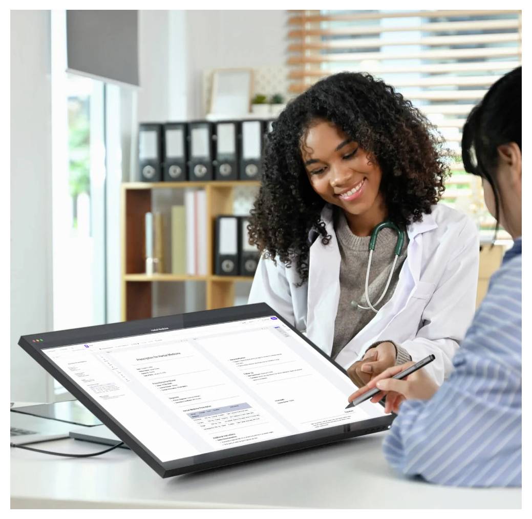 Arzt zeigt einem Patienten medizinische Informationen auf einem großen Touchscreen-Monitor in einem Klinikbüro.