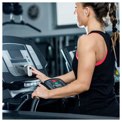 Frau, die ein Ellipsentrainer im Fitnessstudio benutzt, hält die Griffe fest und überprüft während des Trainings die Konsole.