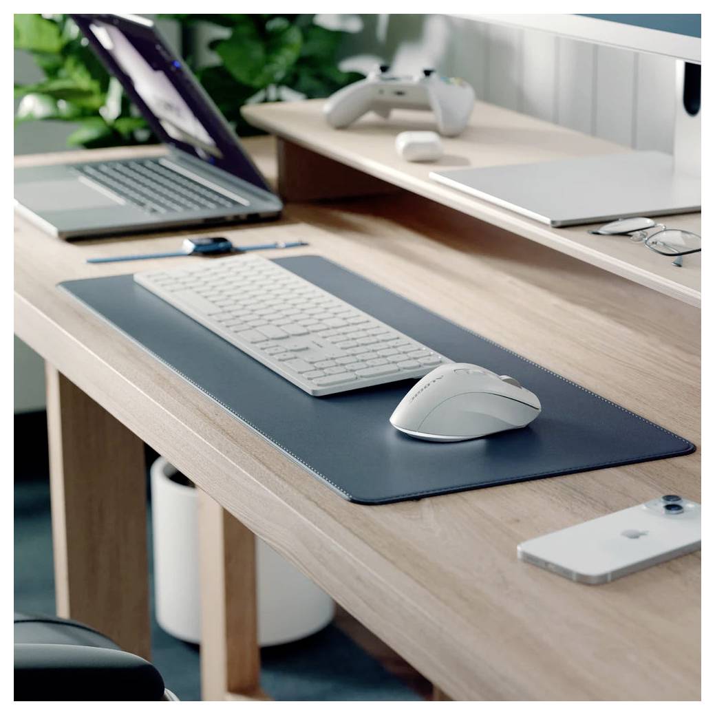 Minimalistischer Home-Office-Schreibtisch mit Laptop, Tastatur, Maus, Spielcontroller, Smartphone und Brille auf einem aufgeräumten Holzarbeitsplatz.