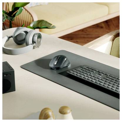 Eine Schreibtischeinrichtung mit einer Tastatur, einer Maus auf einer Matte und Kopfhörern neben einem Computer, was auf einen Home-Office-Arbeitsplatz hindeutet.