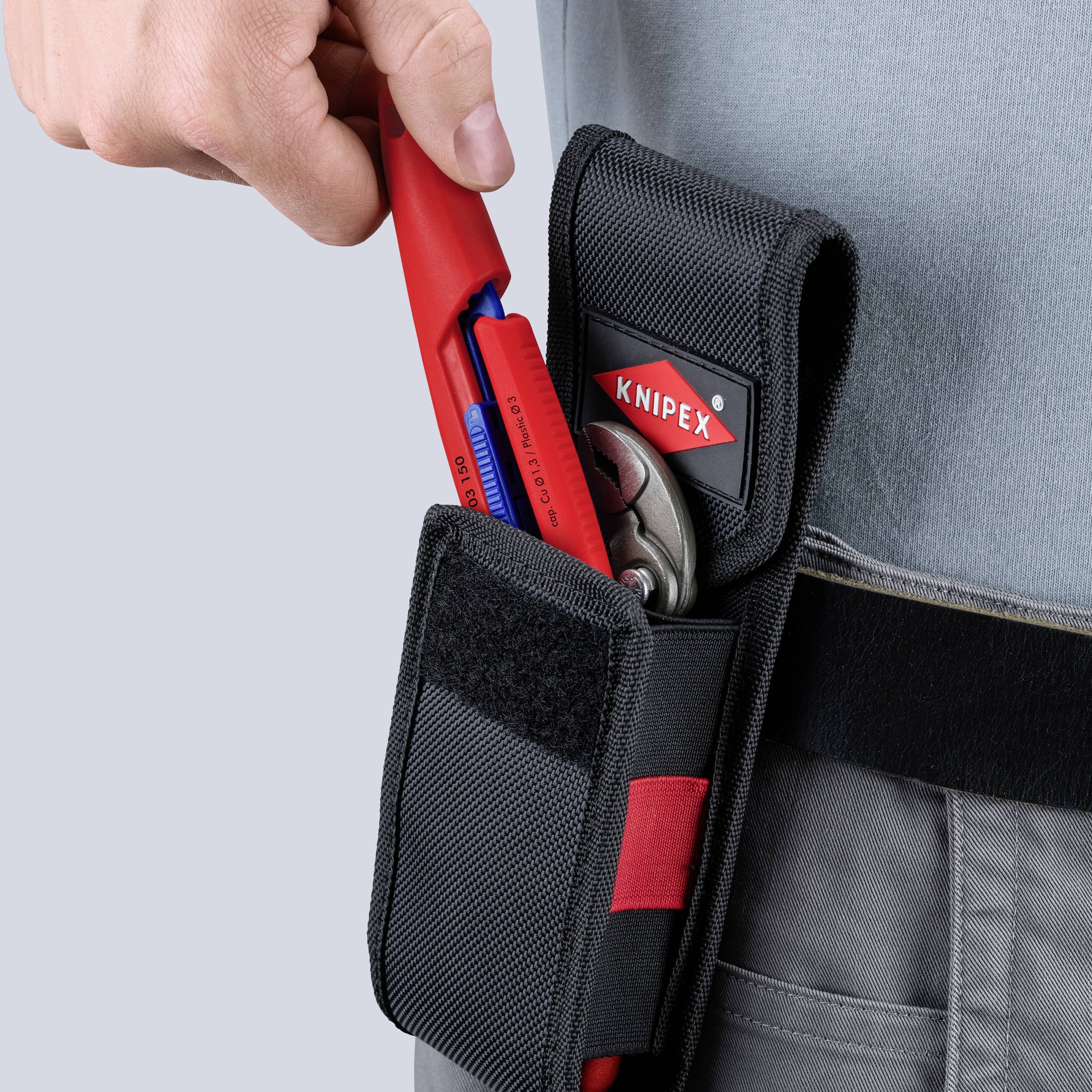 Hand inserting red Knipex Zangen in ein schwarzes Werkzeugetui an einem Arbeitsgürtel, mit einem anderen Werkzeug bereits in der Tasche.