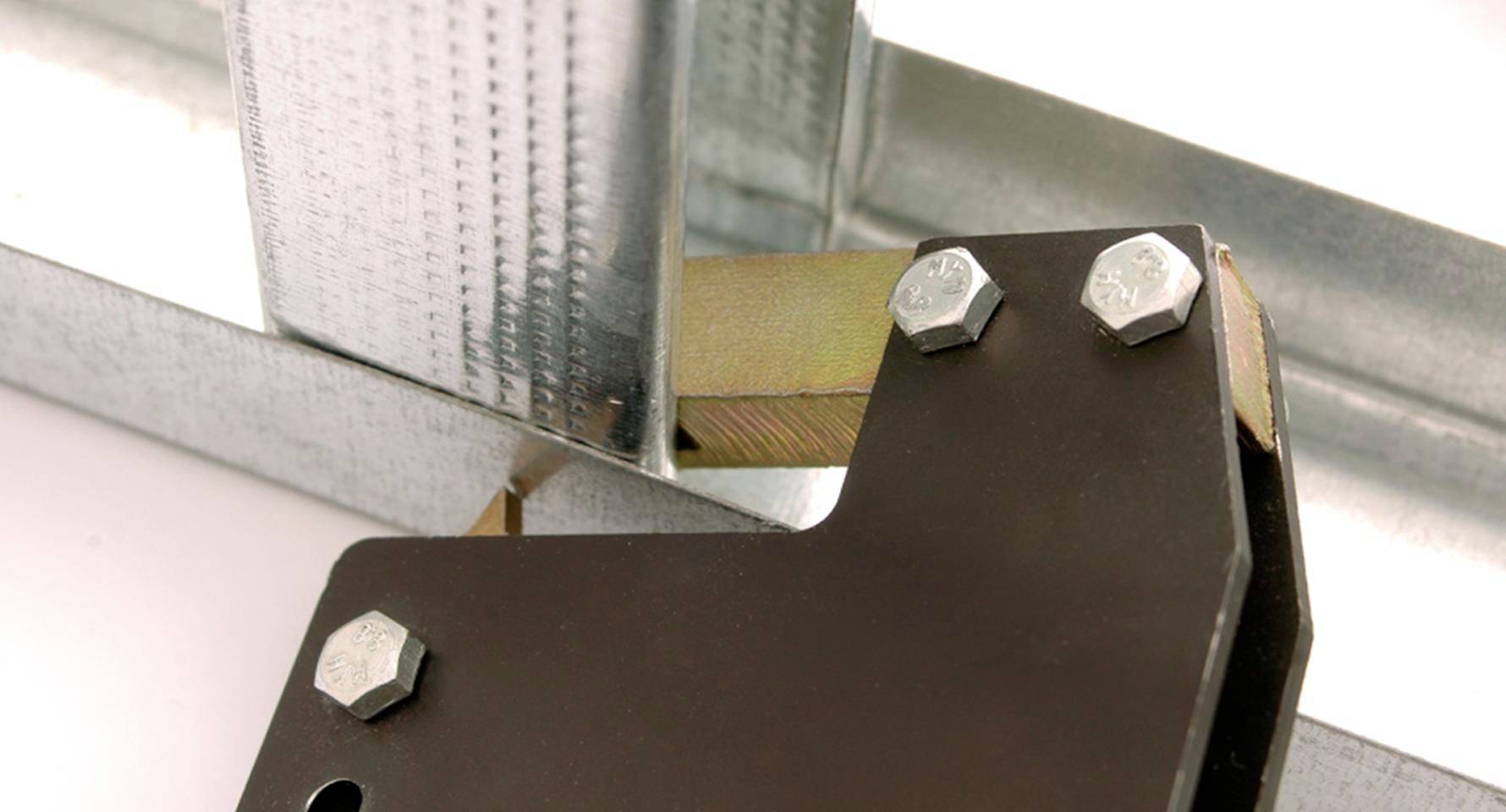 Nahaufnahme einer Metallhalterung mit Bolzen, die einen vertikalen Stahlträger an horizontalen Metallschienen befestigt.