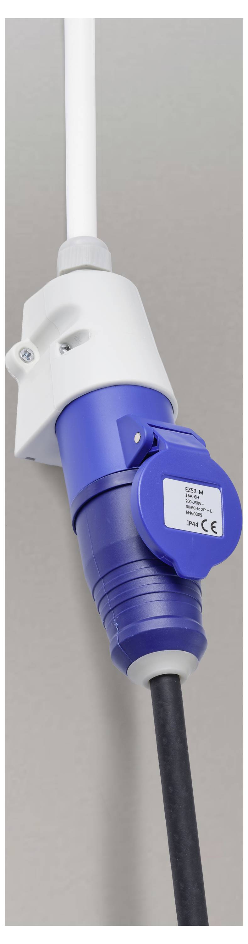 Ein blauer Industrie-Stromstecker, der in eine weiße wandmontierte Steckdose mit an angschlossenenem schwarzem Kabel eingesteckt ist.