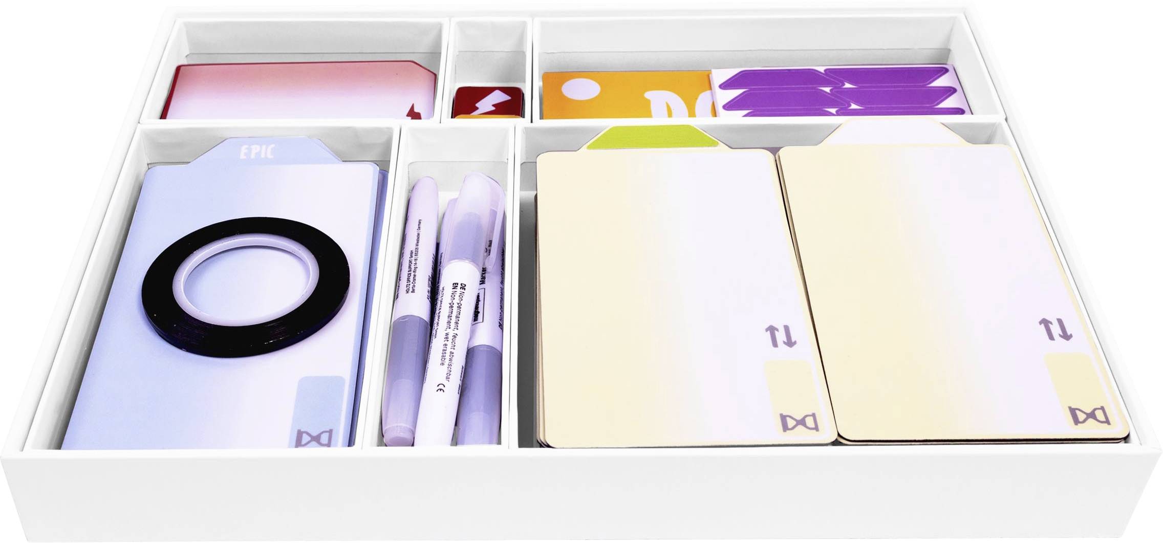 Offene weiße Box mit Fächern, die Schreibwarinartikel enthält, einschließlich Pastellnotizbücher, Stifte und kleine Accessoires auf weißem Hintergrund