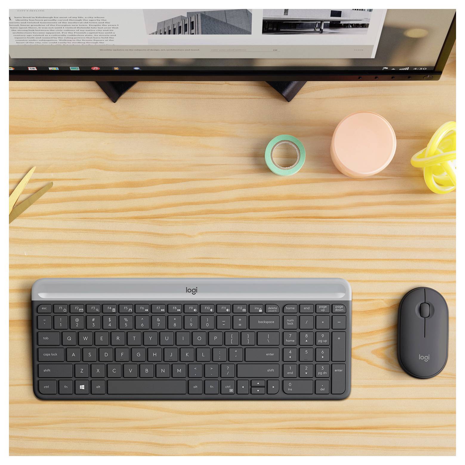 Draufsicht auf einen minimalistischen Schreibtisch mit einem Monitor, einer Tastatur, einer Maus, einer Klebebandrolle, einem Behälter und einem Kabel, mit einer Schere auf der linken Seite.