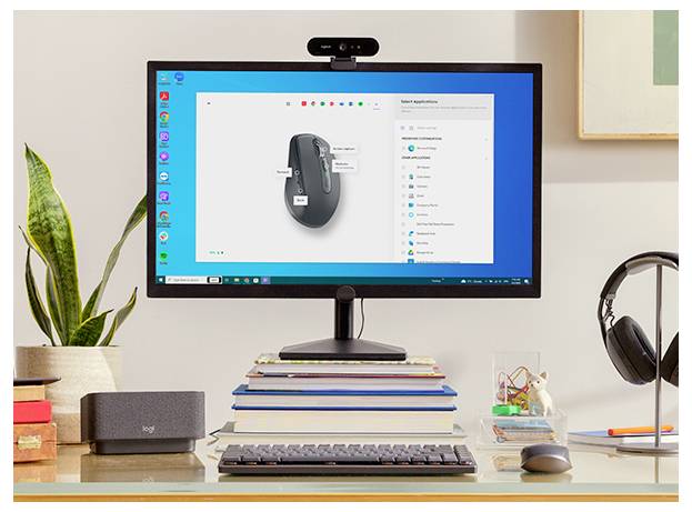 Ein Desktop-Arbeitsplatz mit einem Monitor, auf dem Mauseinstellungen angezeigt werden, einer Tastatur und einer Maus auf einem Bücherstapel, Kopfhörern, einer Pflanze und einer Webcam.