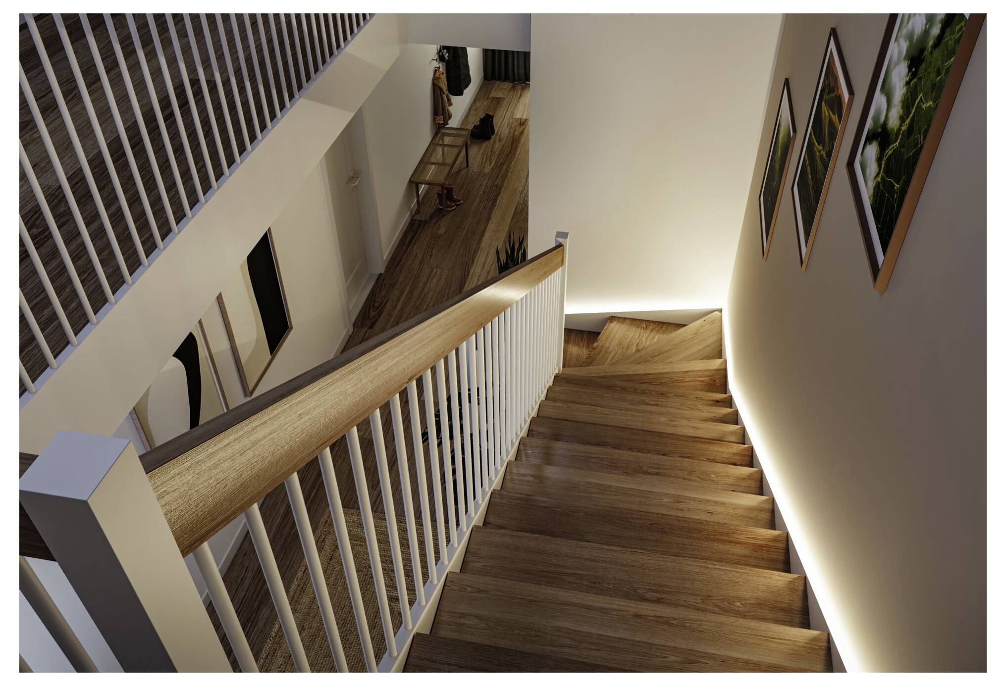 Blick von oben auf eine Holztreppe mit weißen Geländern, beleuchtet durch eine Wandleuchte, mit Blick auf einen Flur darunter mit Garderobe und Wandkunst.