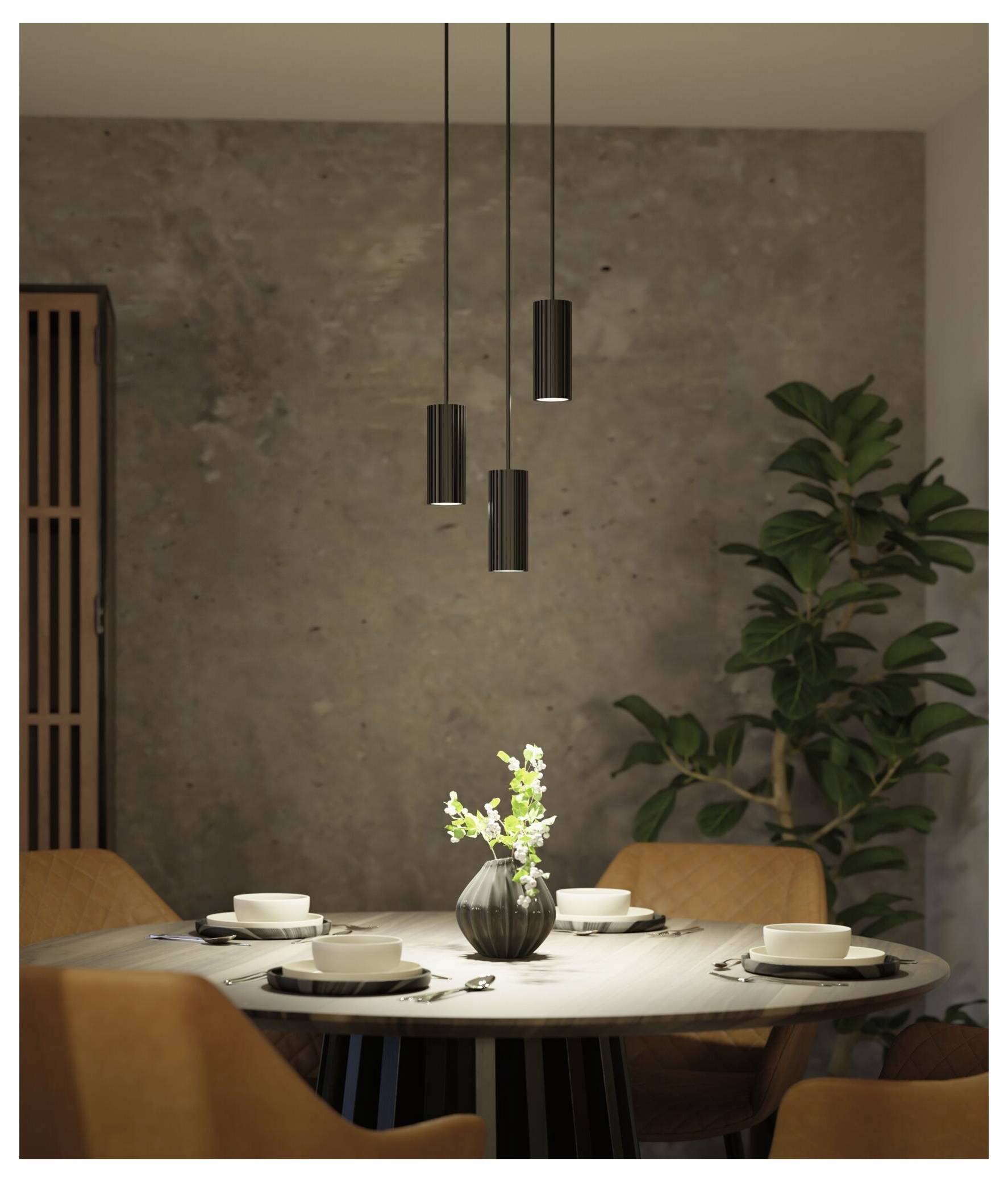 Modernes Esszimmer mit rundem Tisch für vier Personen, hängenden Pendelleuchten, einer Vase als Mittelstück und einer großen Topfpflanze.
