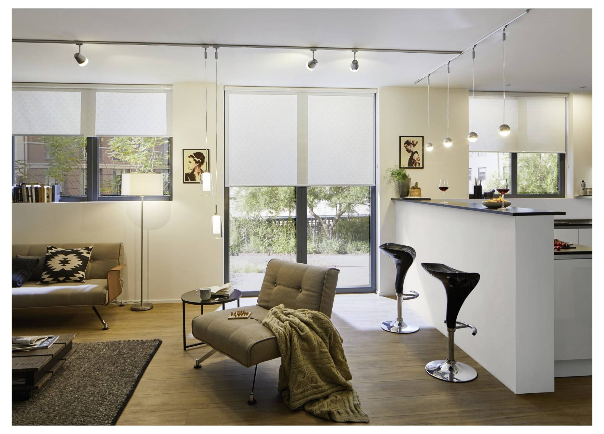 Modernes Wohnzimmer mit offener Grundrissgestaltung und Küche mit Sofa, Loungesessel, Barhockern und großen Fenstern mit Jalousien.