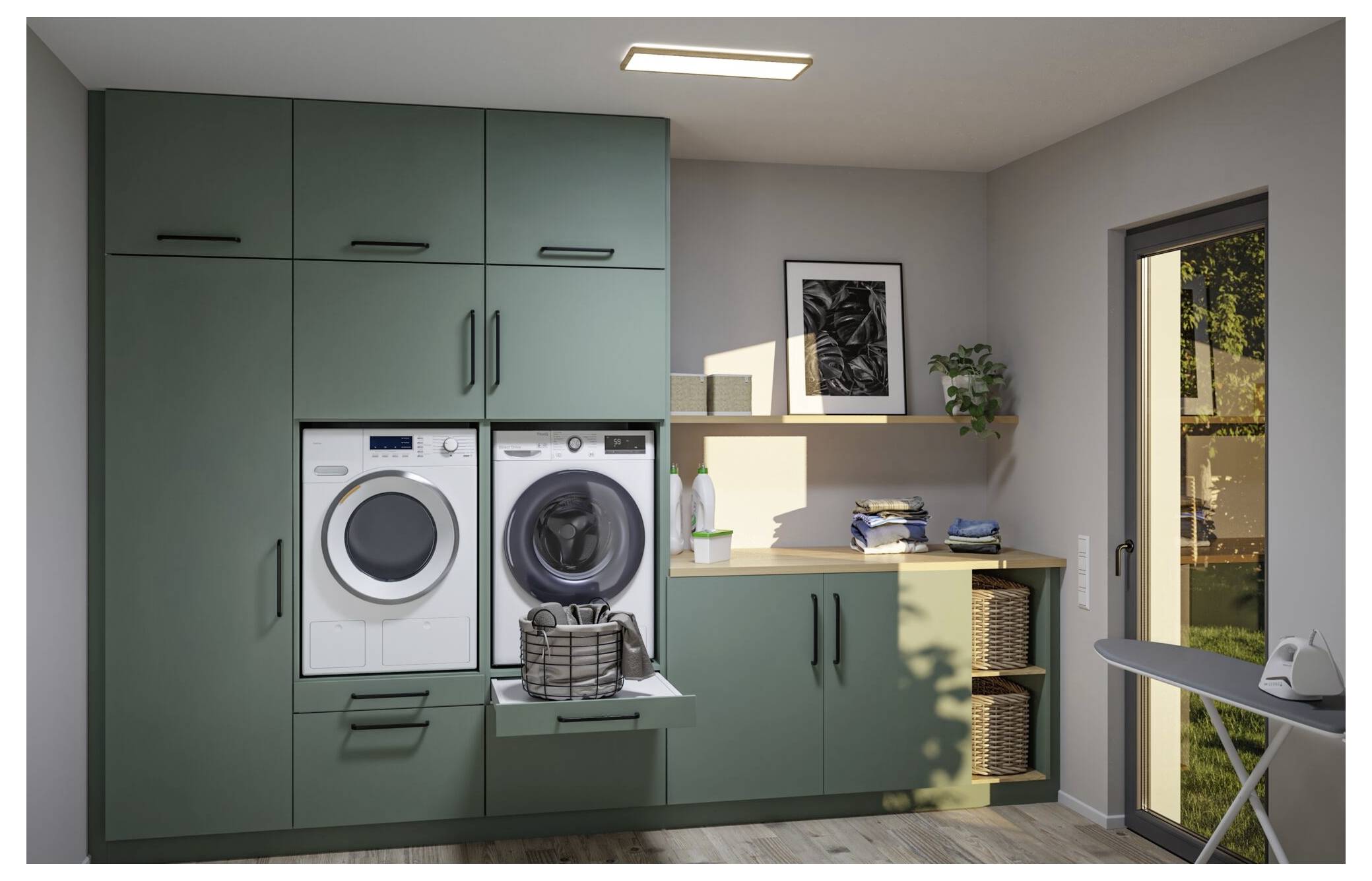 Modernes Waschzimmer mit grünen Schränken, übereinander gestapelter Wasch- und Trocknmaschine, Falttisch, Regalen und einer Glastür nach außen.