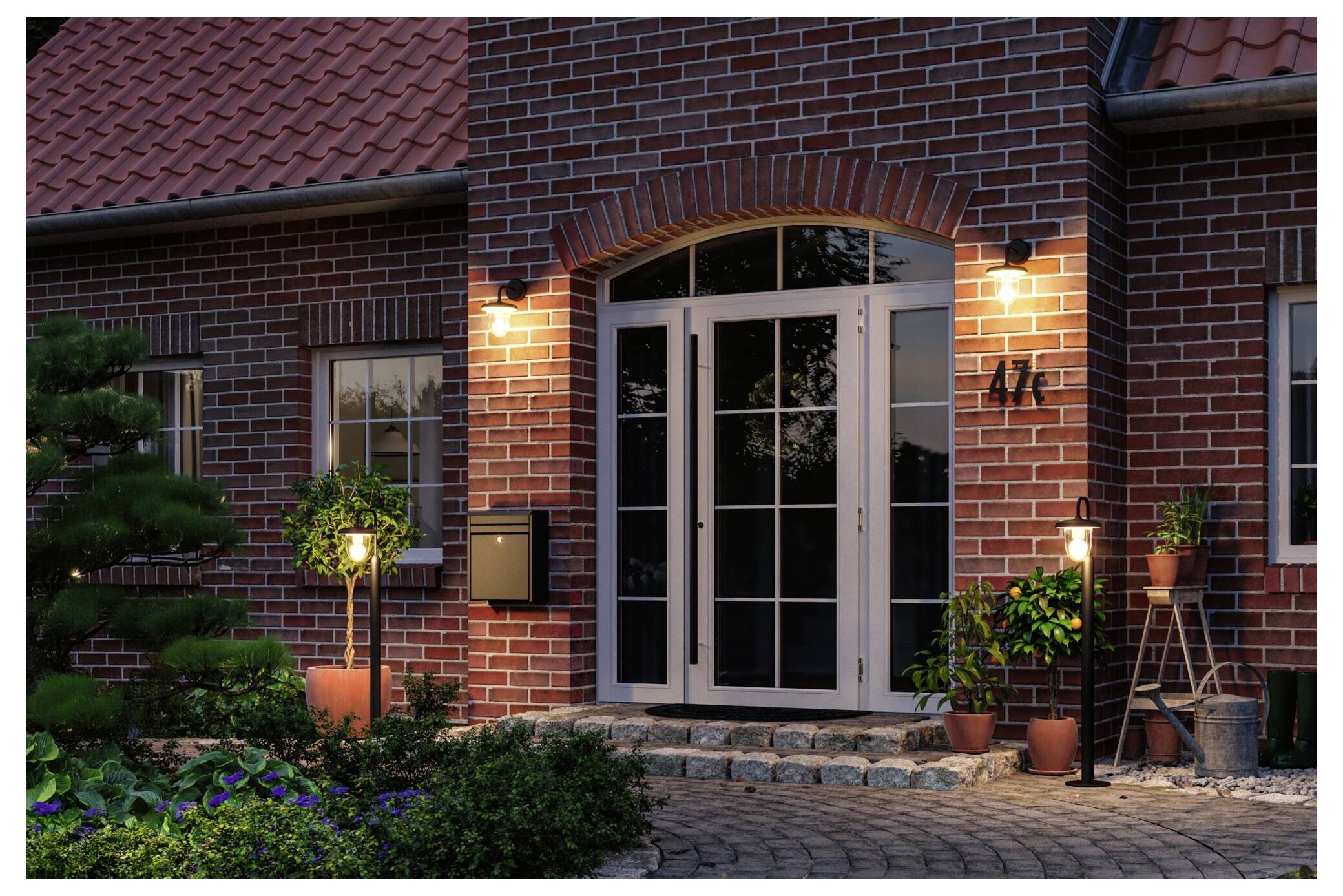 Backsteinhaus-Eingang in der Dämmerung mit beleuchteten doppelflügligen Türen, Hausnummer 417, Topfpflanzen und einem gestalteten Vorgarten.