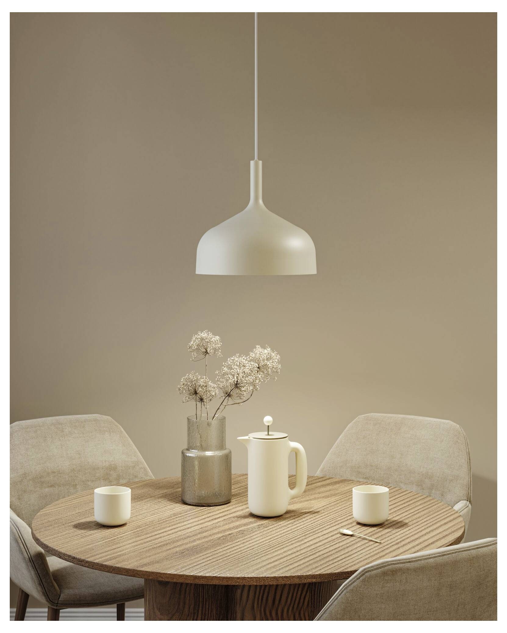 Runder Holzesstisch mit vier beigen Stühlen, hängende Pendelleuchte und einfache Keramikdekoration in einem Raum mit neutralen Tönen.