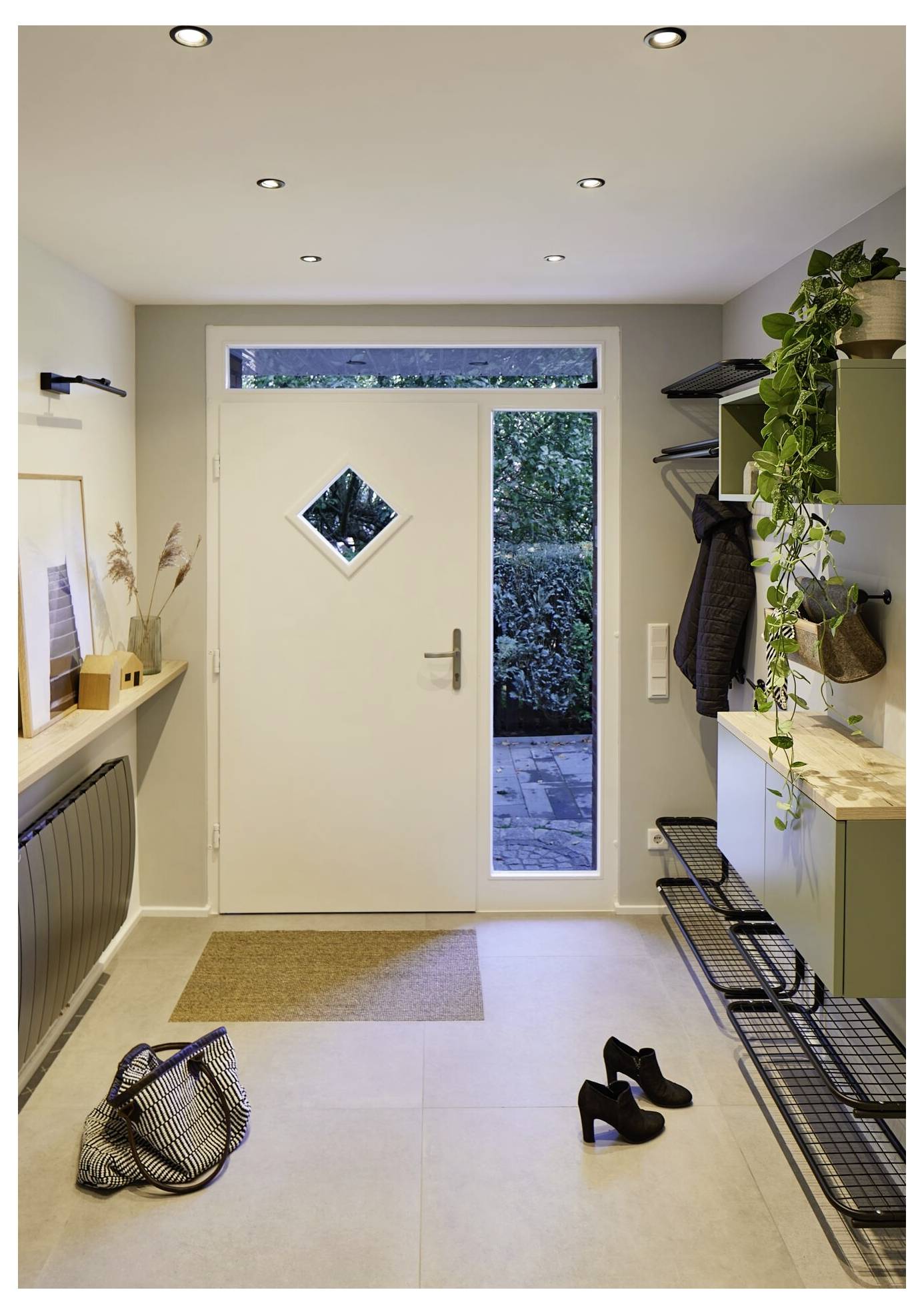 Moderner Flur mit Holzboden, Konsolentisch und Spiegel, Pflanzen, Treppe auf der rechten Seite und Glastüren, die am Ende zu einem Garten führen.