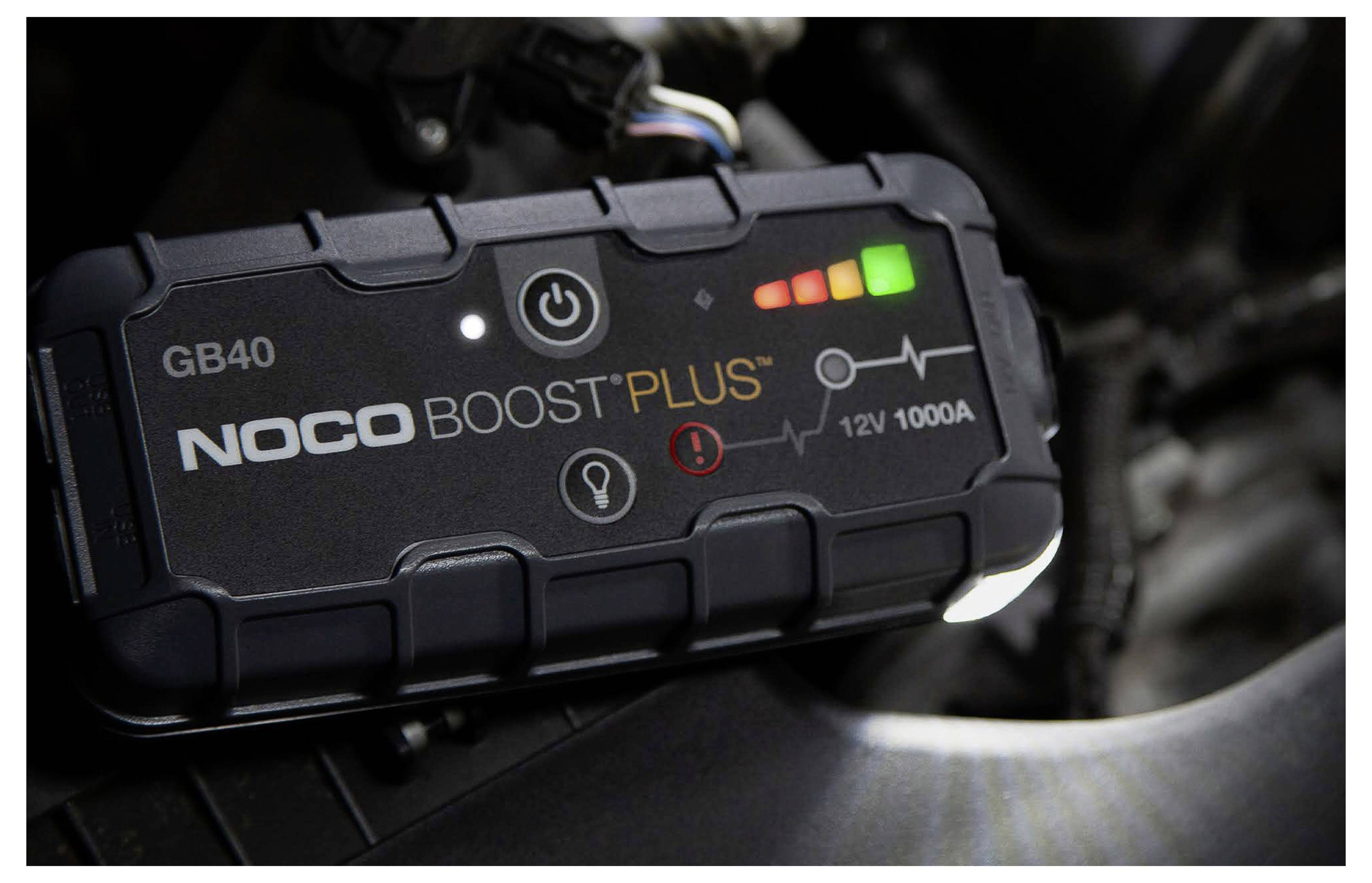Tragbarer NOCO Boost Plus GB40 Starthilfegerät in einem Auto, zeigt Einschaltknopf, Ladeindikatoren und die Bezeichnung „12V 1000A