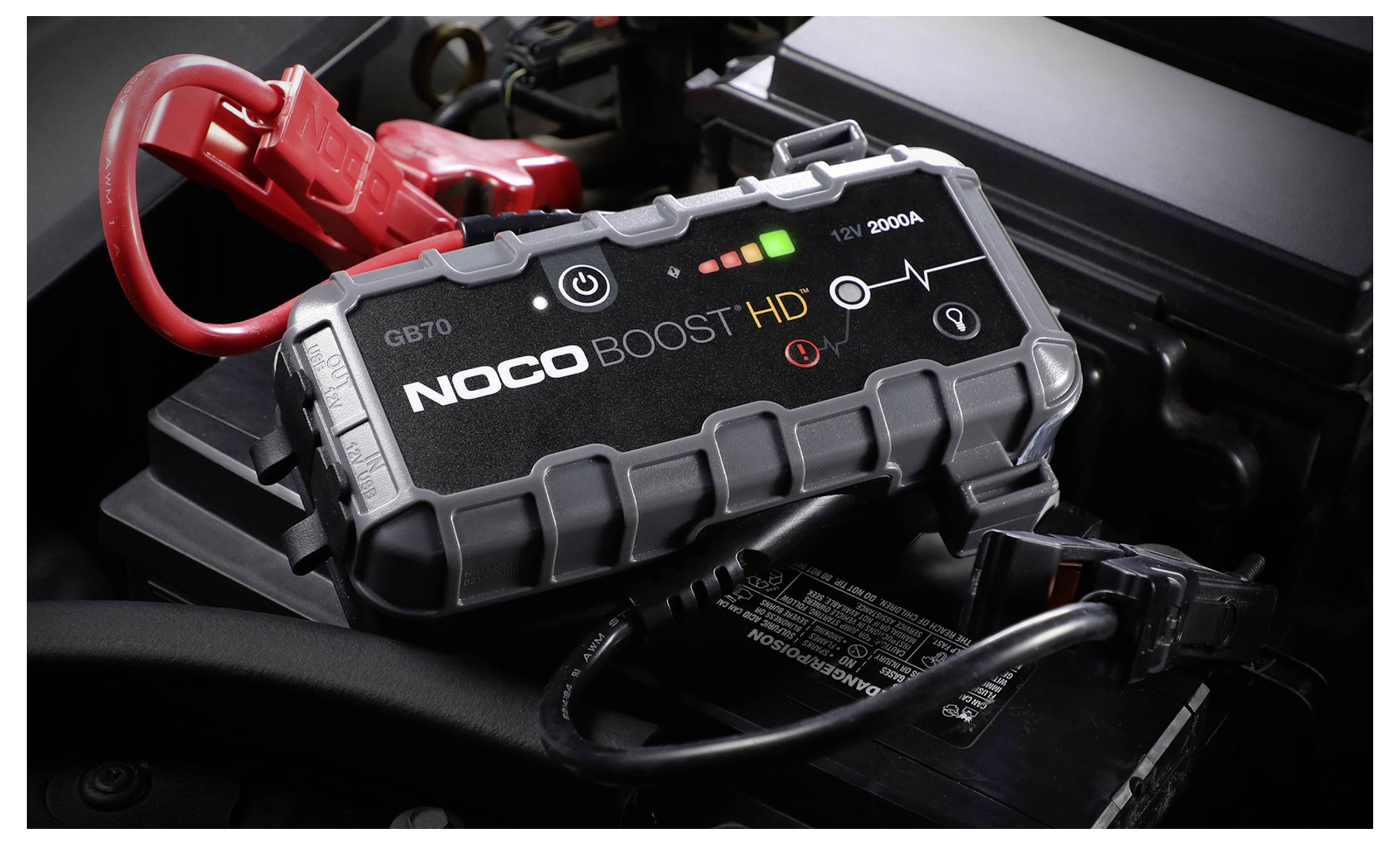 NOCO Boost HD tragbarer Autostarthilfegerät mit roten und schwarzen Klemmen, die mit einer Fahrzeugbatterie verbunden sind.