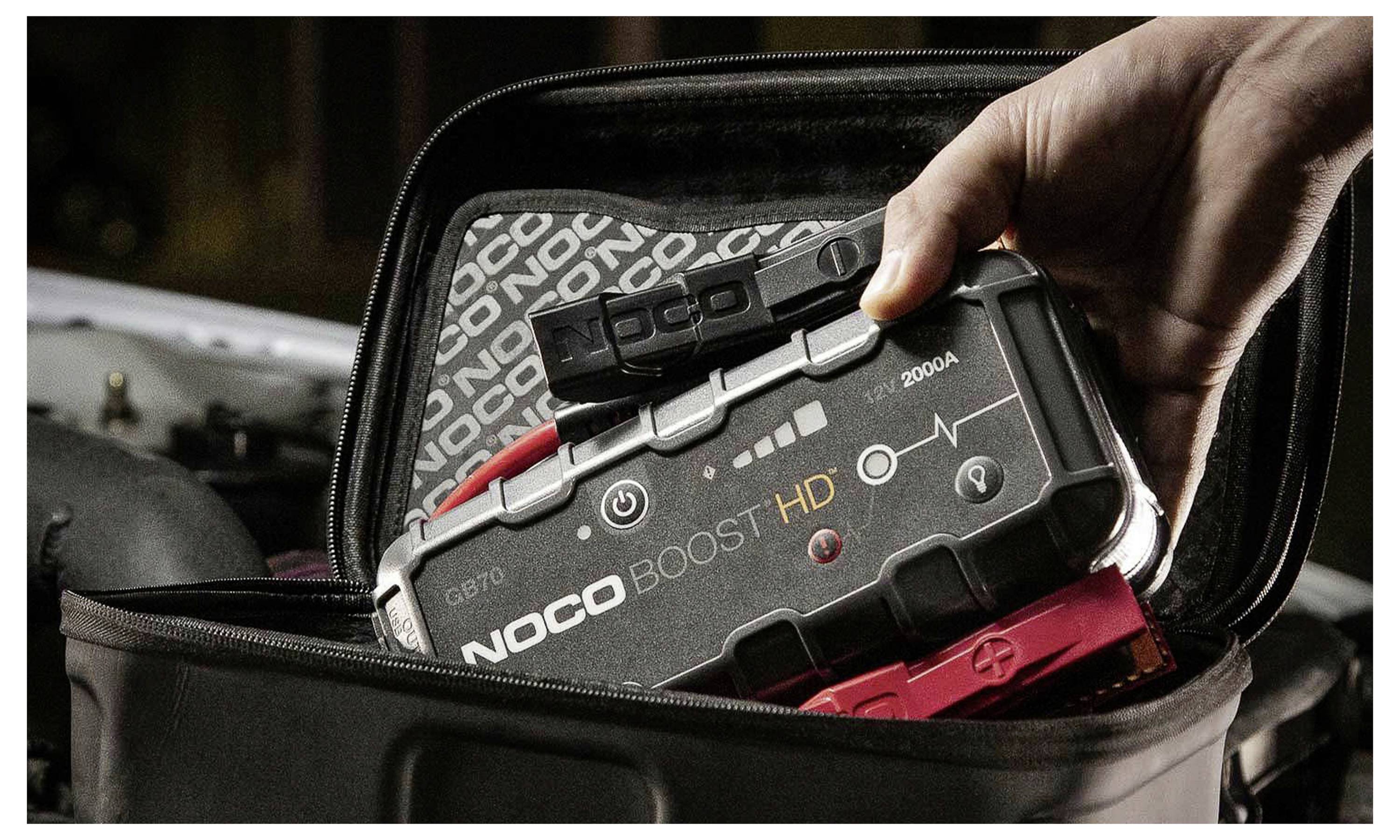 Hand legt ein NOCO Boost HD tragbares Starthilfegerät in eine offene Tragetasche.