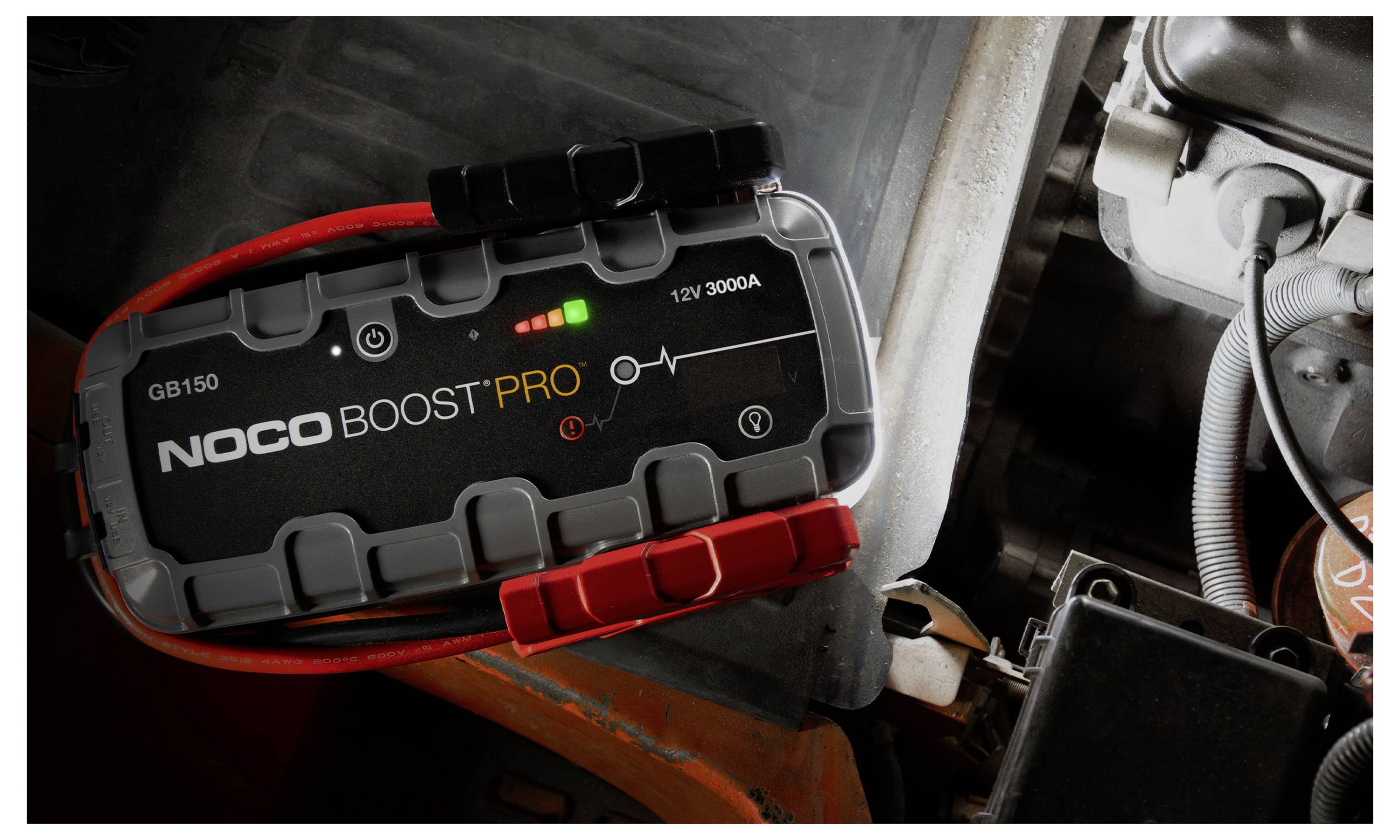 NOCO Boost Pro tragbarer Autostarthilfegerät, das in einem Motorraum angeschlossen ist, mit Anzeigelichtern, die den Stromversorgungsstatus anzeigen.