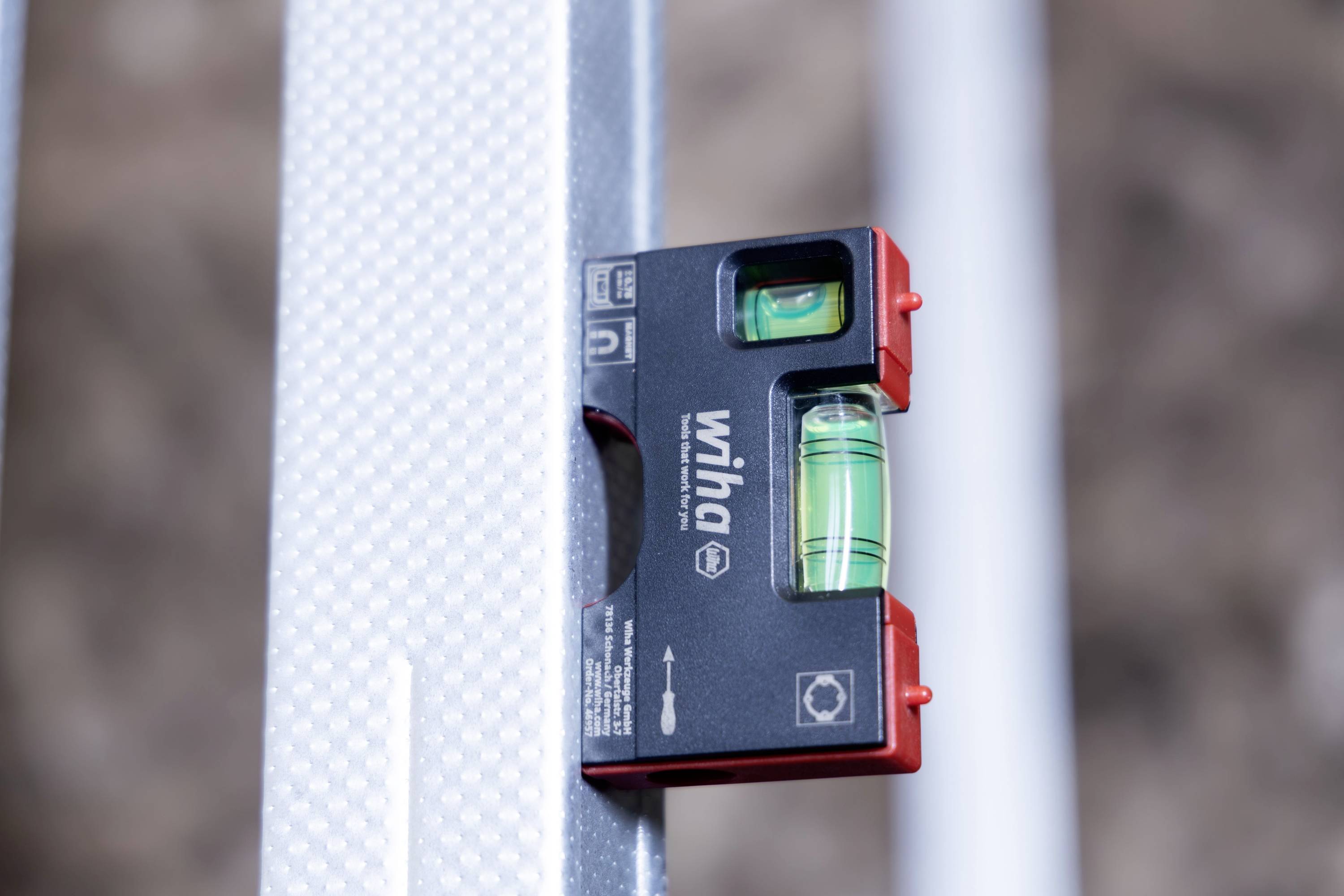 Nahaufnahme einer an einem Metallpfosten angebrachten Wasserwaage, die die zentrierte Blase zur Ausrichtung zeigt.