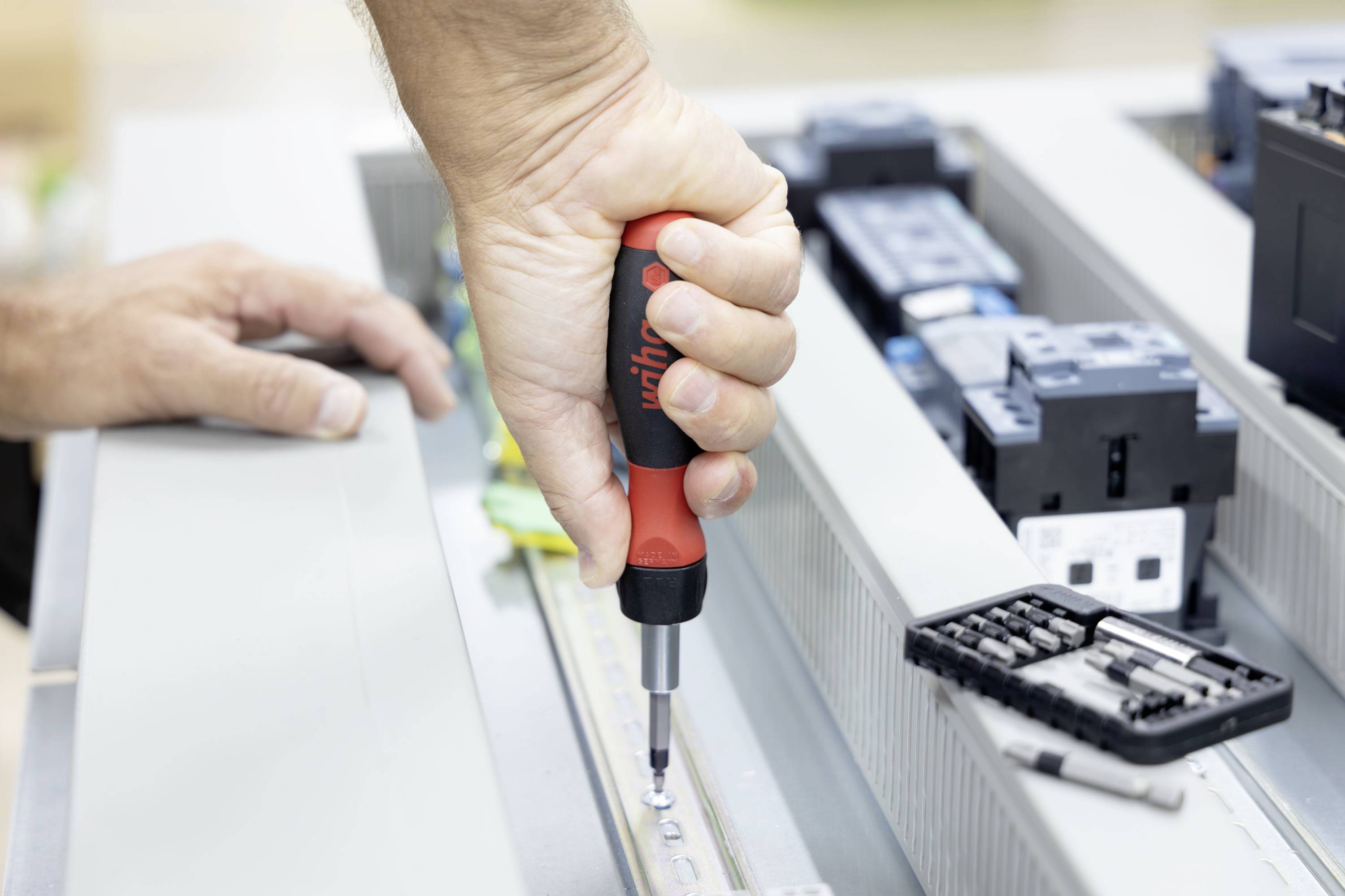 Eine Person benutzt einen Schraubenzieher, um eine Schraube in einem offenen elektronischen Gerät während der Montage oder Reparatur festzuziehen.