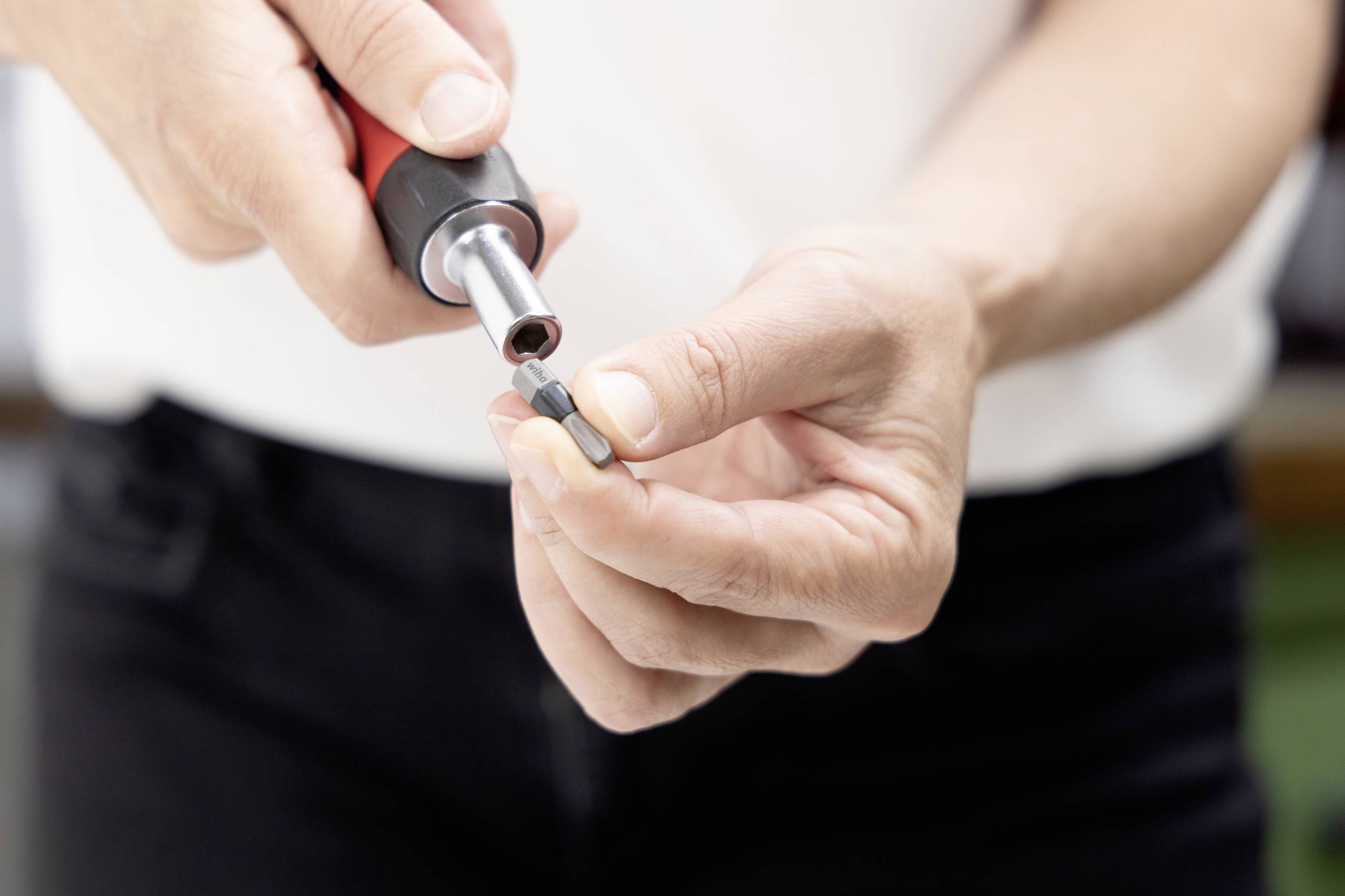 Nahaufnahme von Händen, die einen Schraubendreher verwenden, um eine kleine Schraube oder ein Befestigungselement anzuziehen.