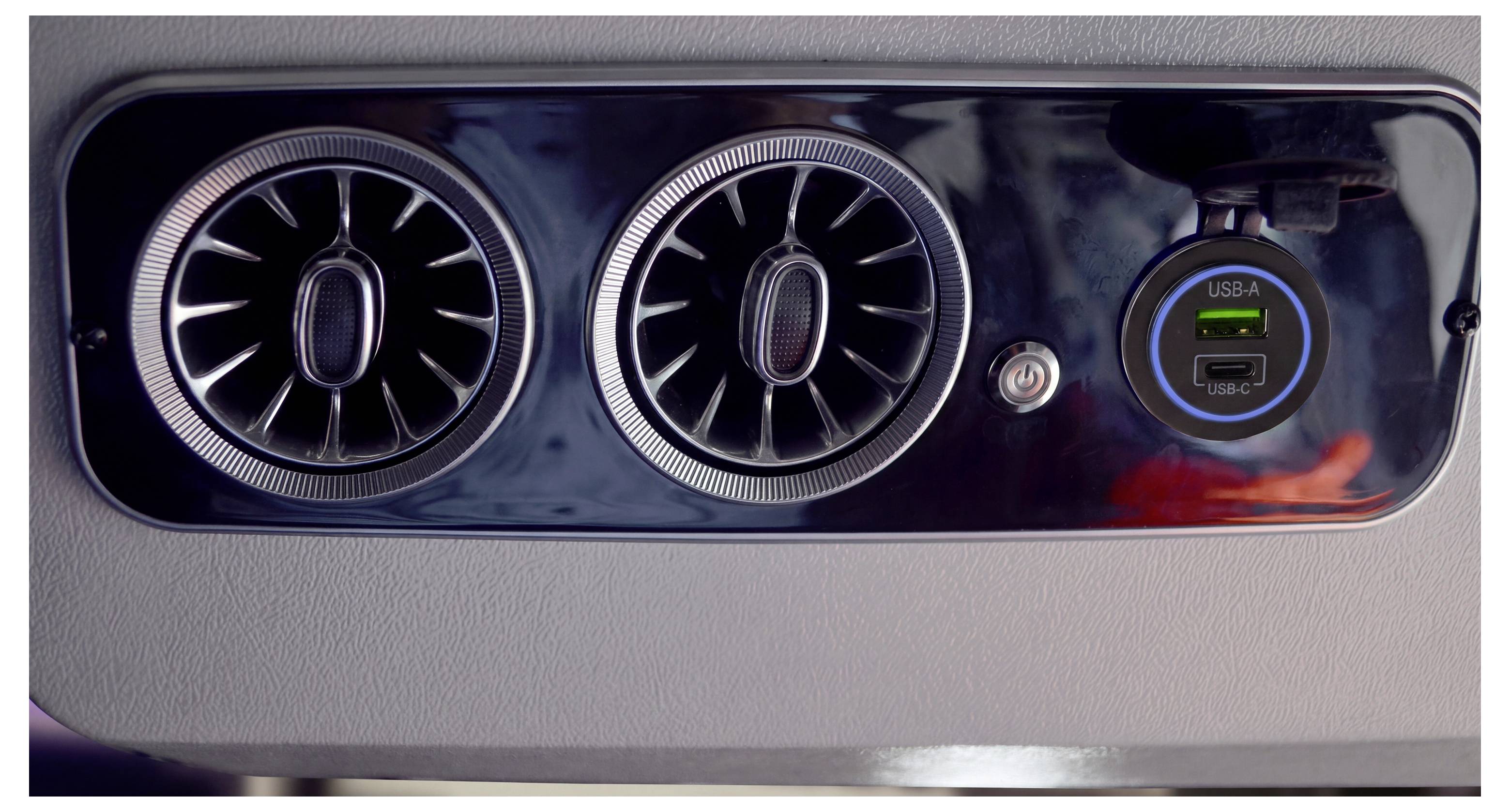 Heckkonsole des Autos mit zwei runden Lüftungsöffnungen und einem USB-A-/USB-C-Ladeanschluss mit blauen Anzeigelichtern.