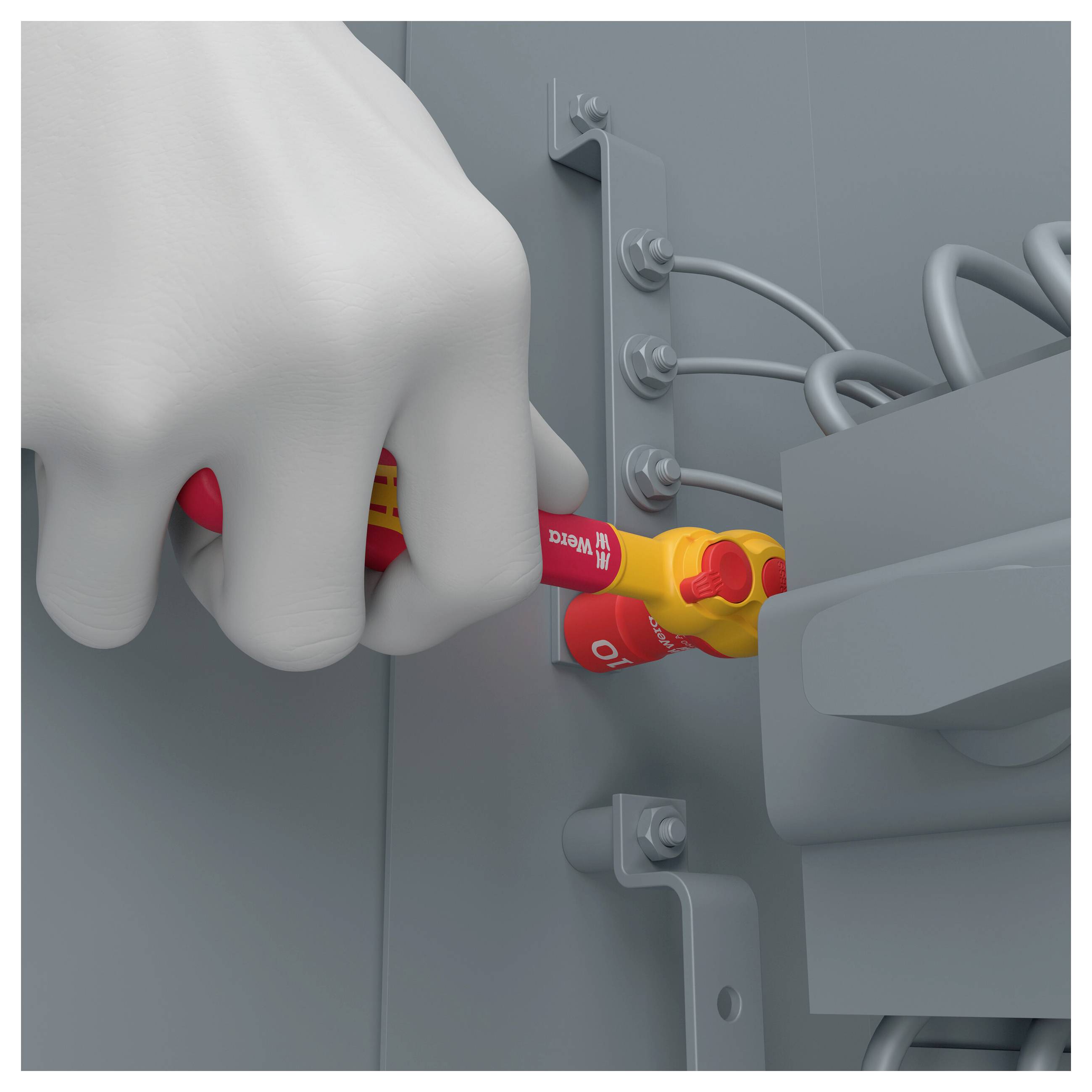 Eine behandschuhte Hand führt ein rotes isoliertes Elektrowerkzeug in ein graues Bedienfeld ein, was auf sichere Wartungs- oder Reparaturarbeiten hindeutet.