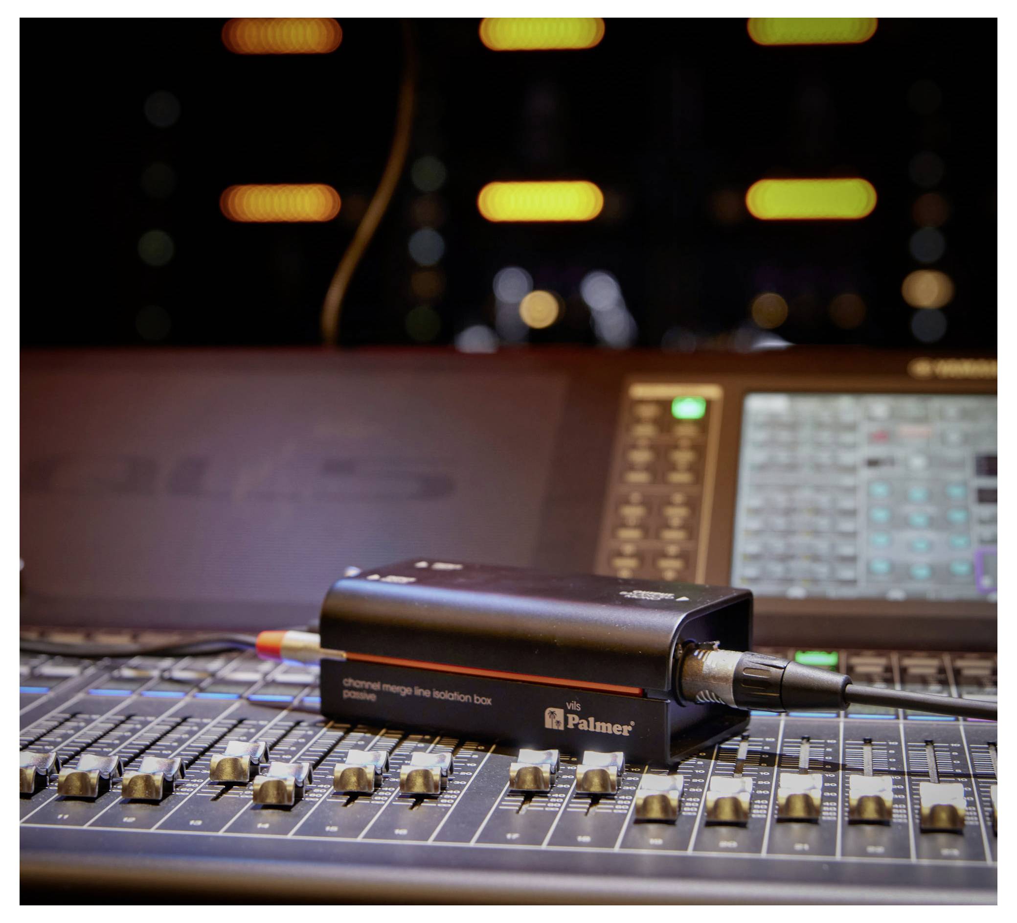 Audiomischpult mit einer kleinen Palmer-Box und angeschlossenen Kabeln, die auf den Fadern in einem Recording- oder Tonstudio ruhen.