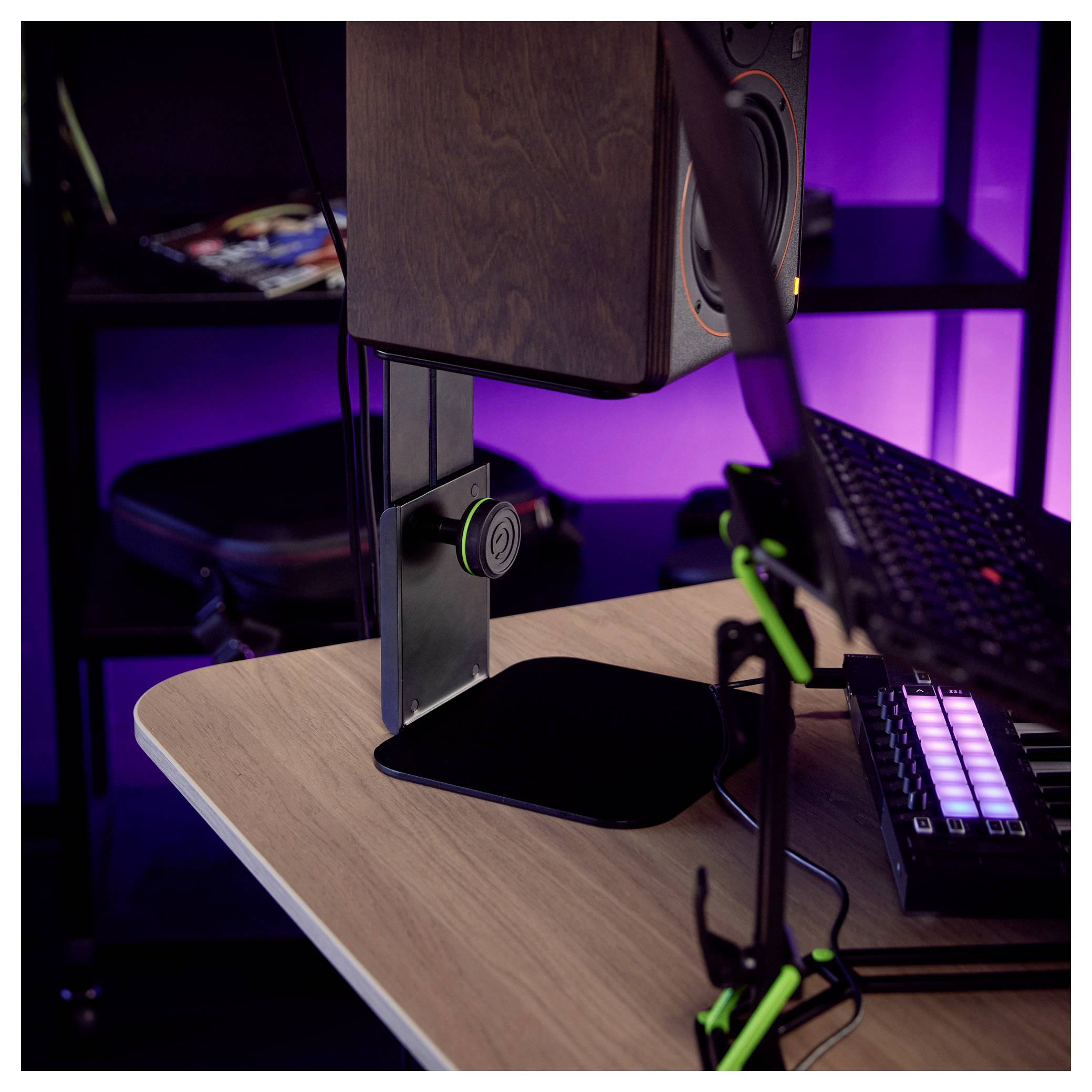 Eine Computer-Schreibtischkonfiguration mit einem großen Monitor auf einem verstellbaren Ständer, einer Tastatur und einem Mikrofonarm in einem violett beleuchteten Raum.