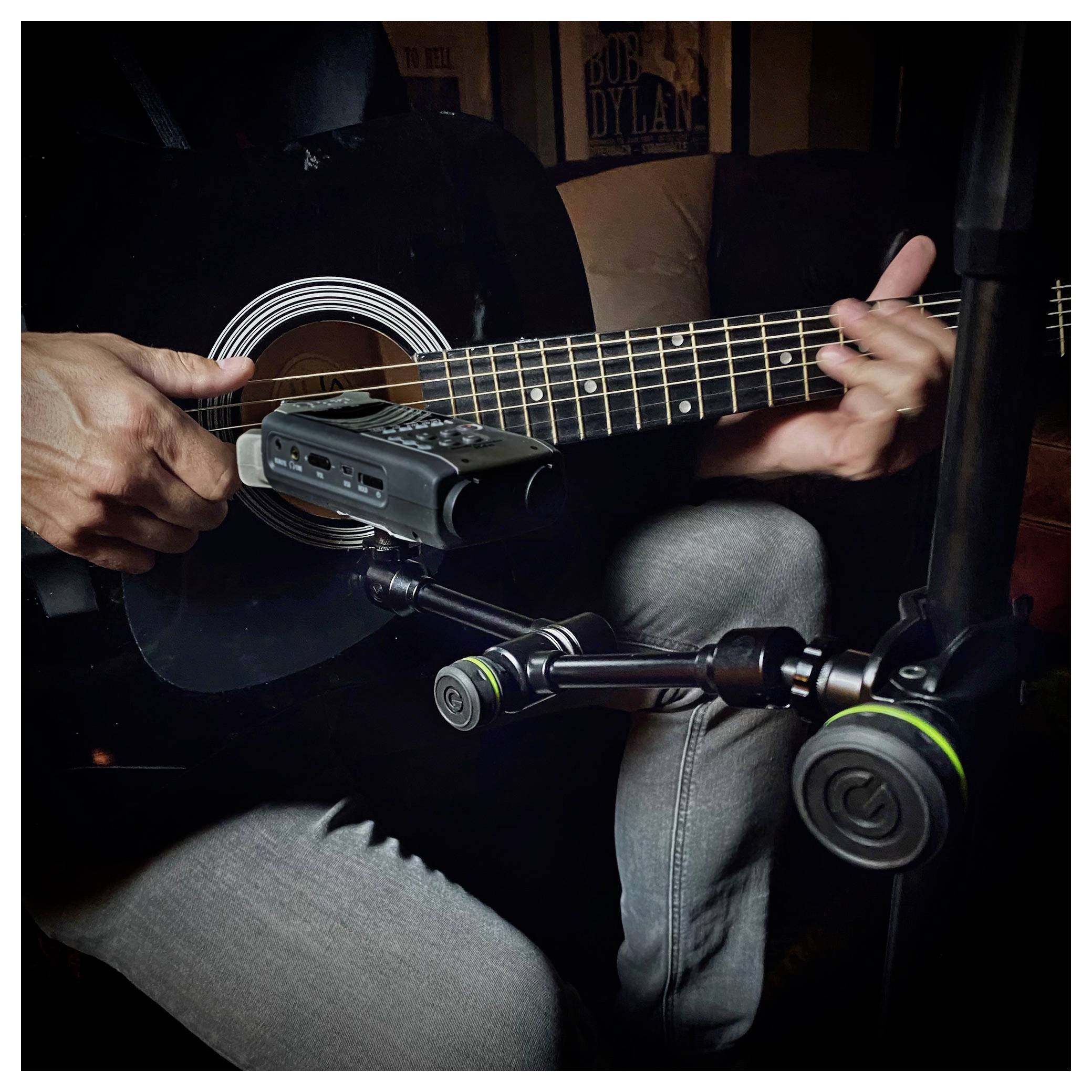 Nahaufnahme einer Person, die eine schwarze Akustikgitarre spielt, mit einem Mikrophon-Rekorder in der Nähe des Schalllochs, um die Musik aufzunehmen.