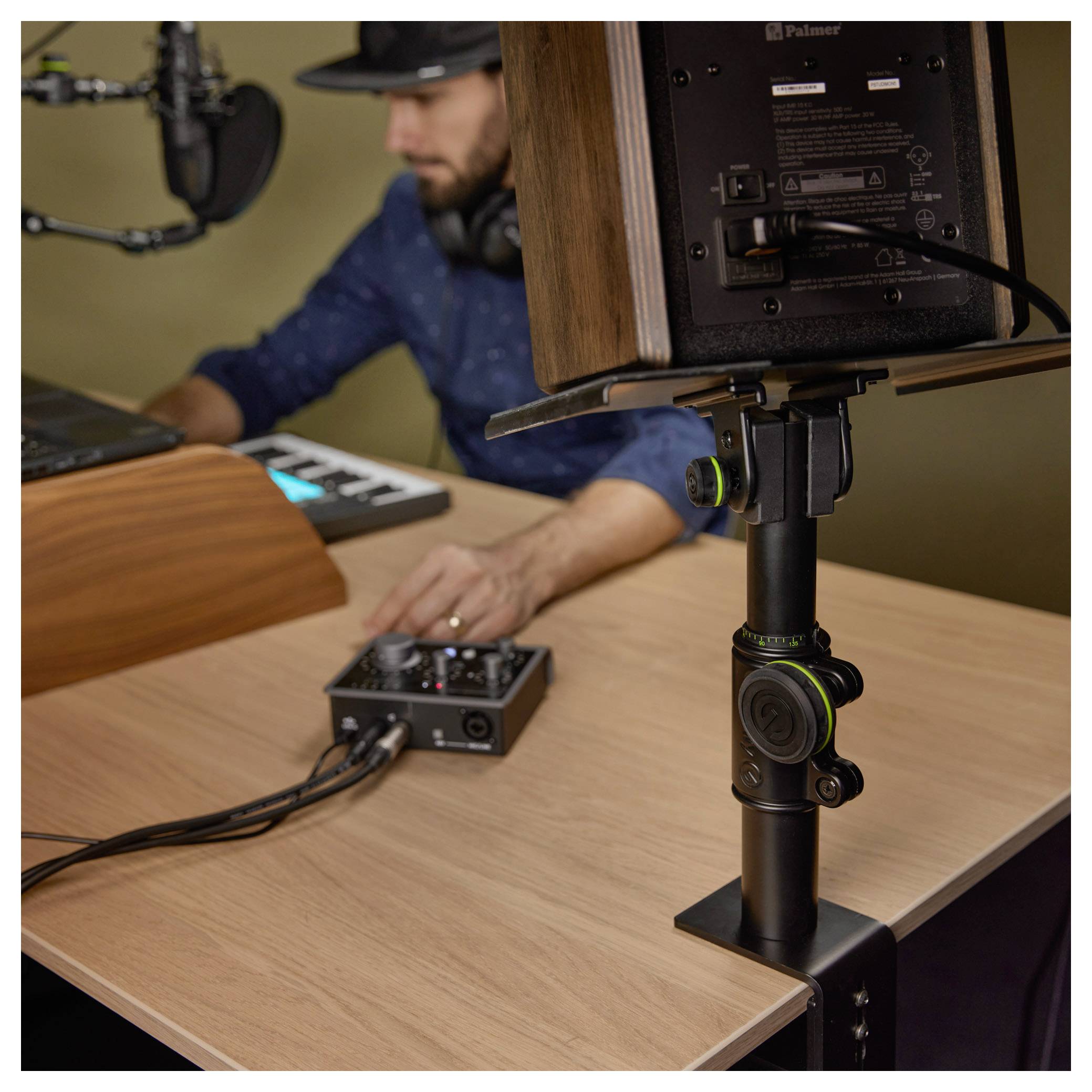 Podcast-Aufnahmeeinrichtung mit Mikrofon, Kameramonitor und Audio-Mixer, während eine Person die Ausrüstung an einem Schreibtisch anpasst