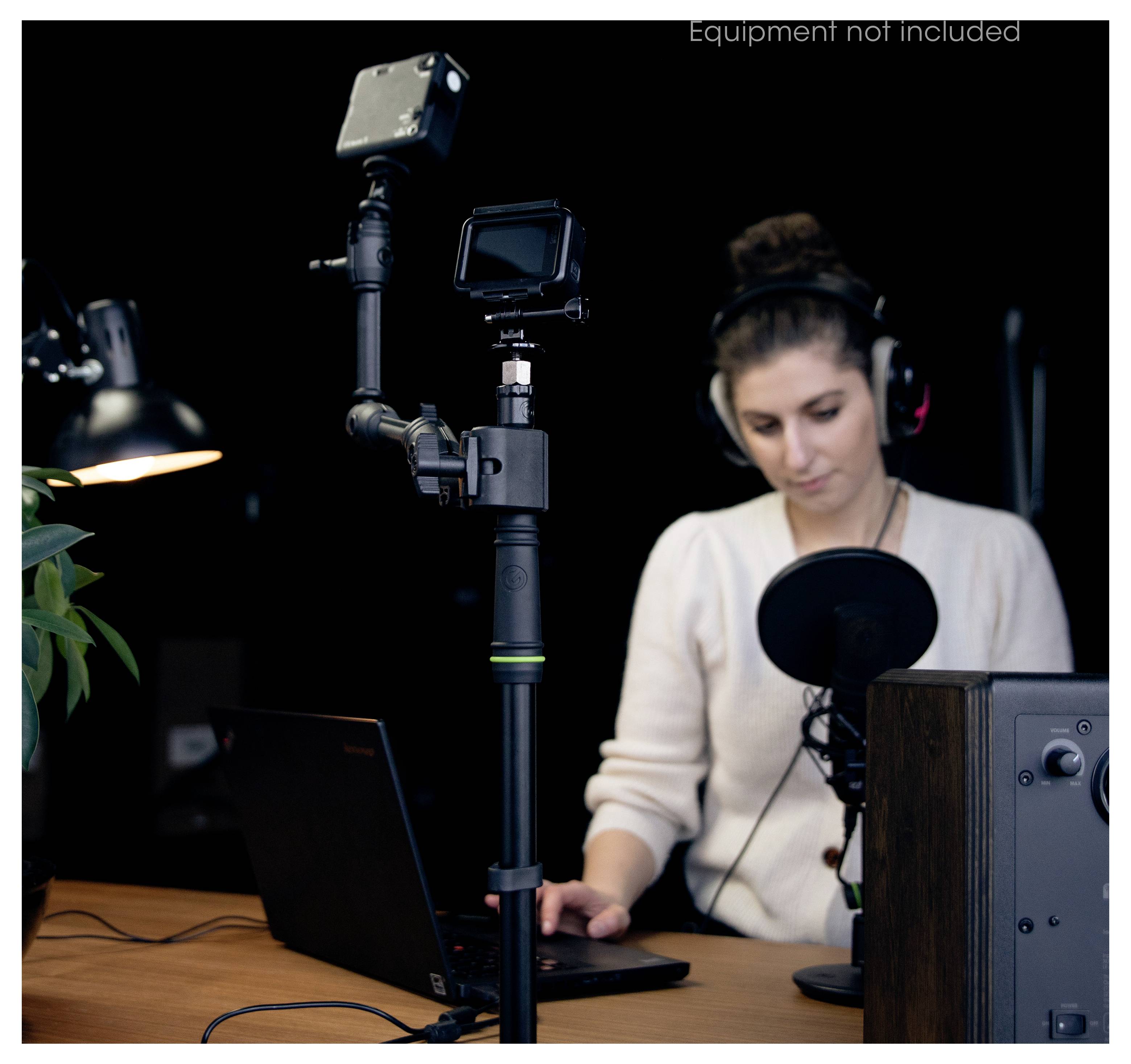 Frau, die an einem Schreibtisch Audio oder Video mit einem Laptop, Mikrofon und Kamera auf einem Stativ in einem Studio-Setup aufnimmt.