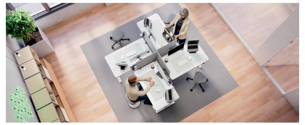 Luftansicht von zwei Personen, die an separaten Schreibtischen in einem modernen offenen Büro mit Computern und Stühlen arbeiten.